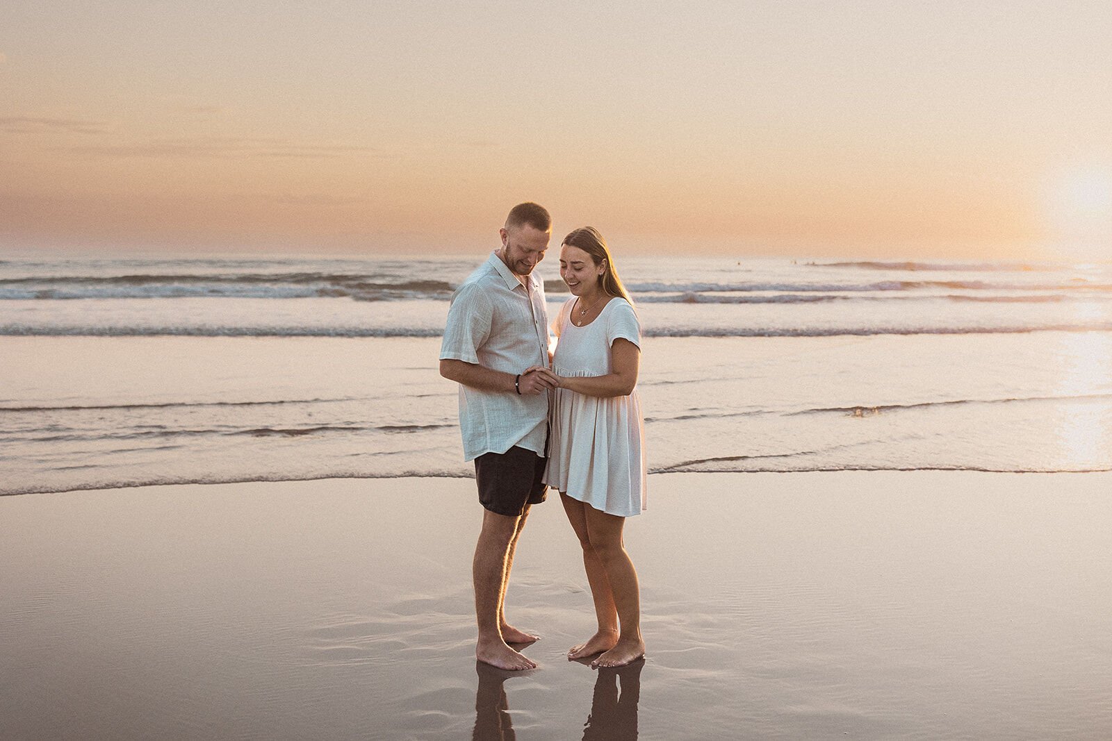 Couple holding hands in the shallow water, Charlie and Hannah's sunrise marriage proposal at Broken Head Beach, Byron Bay