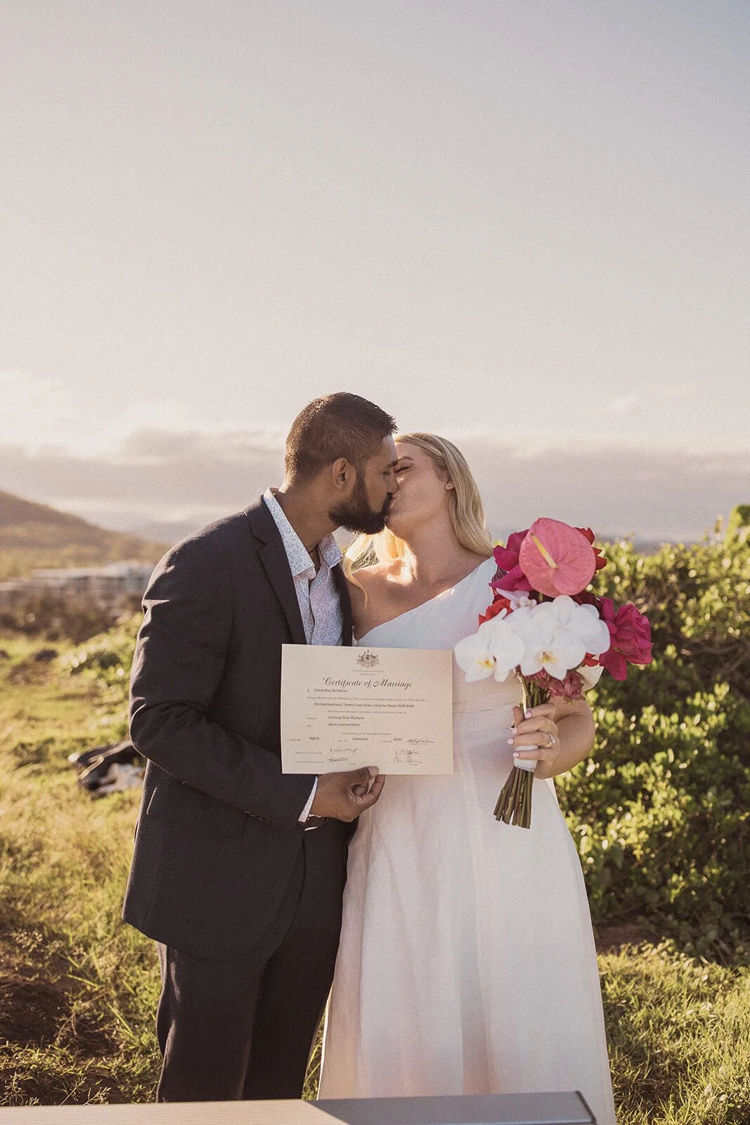 Couple kissing while holding their marriage certificate, Brittany and Mark's elopement at Cabarita Beach, Northern Rivers