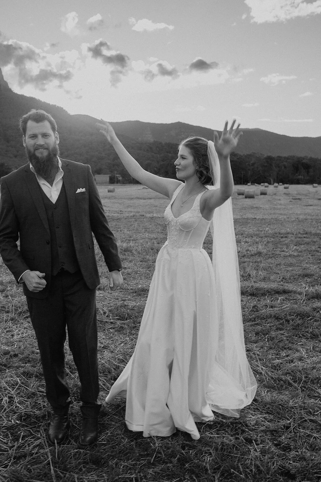 Black and white of the bride waving her arm in joy, Sam and Tom's elopement at Highfield Farm, Northern Rivers