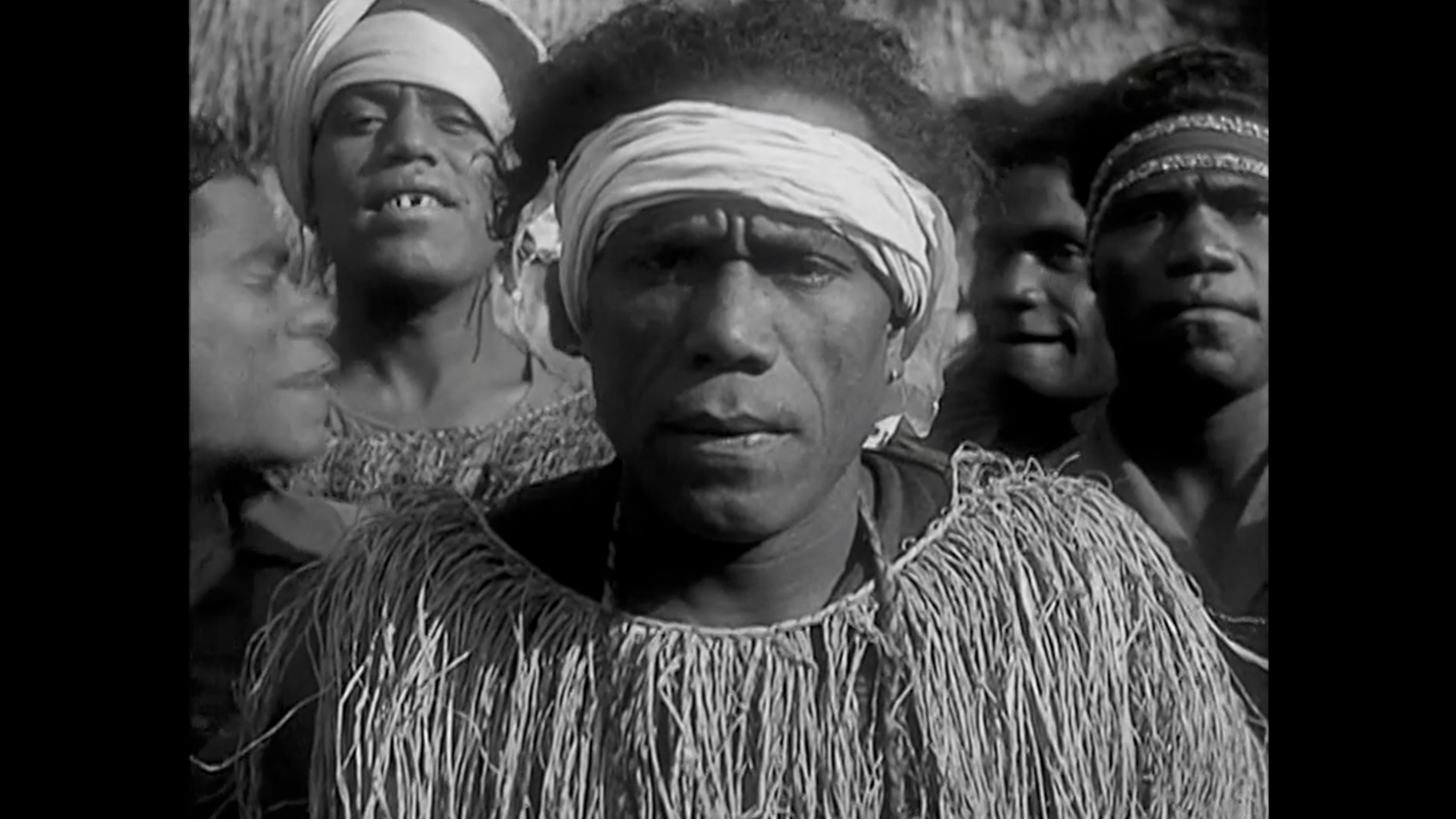 Un groupe d'hommes africains portant des vêtements traditionnels, certains avec des turbans, dans une scène en noir et blanc.