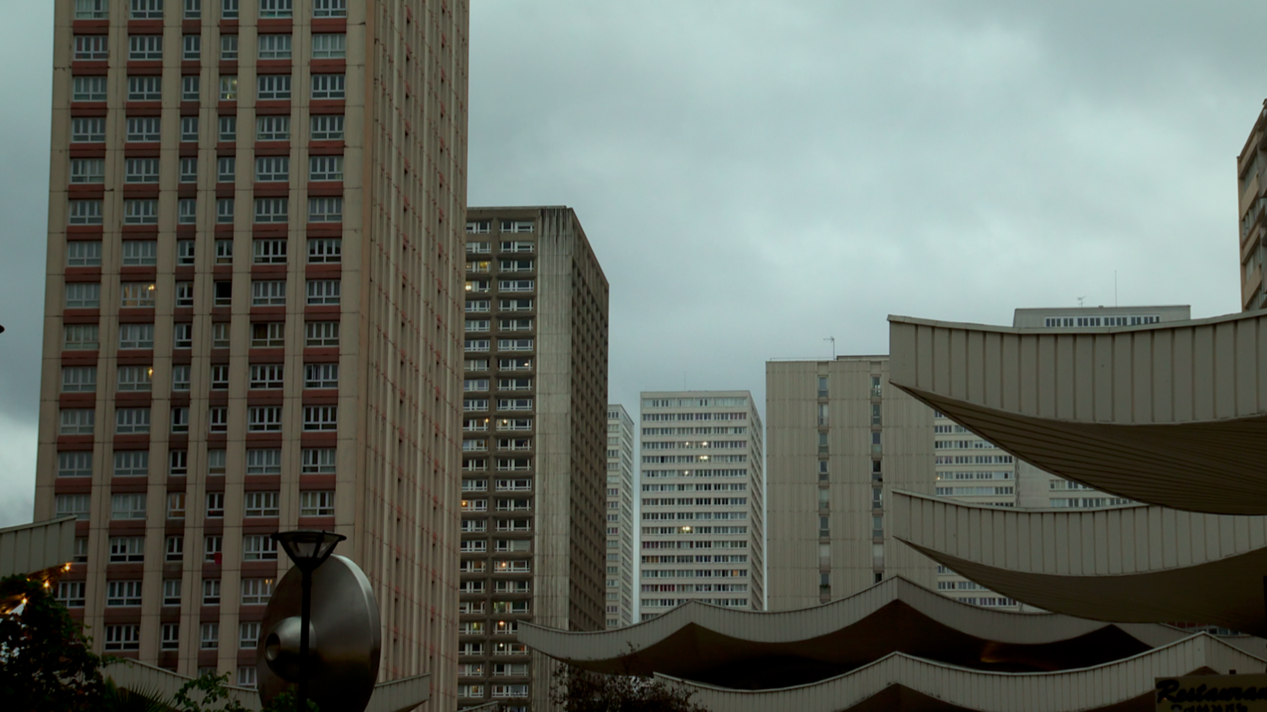 Gratte-ciel résidentiel à Paris avec des bâtiments modernes en béton, un ciel nuageux et un aménagement urbain.