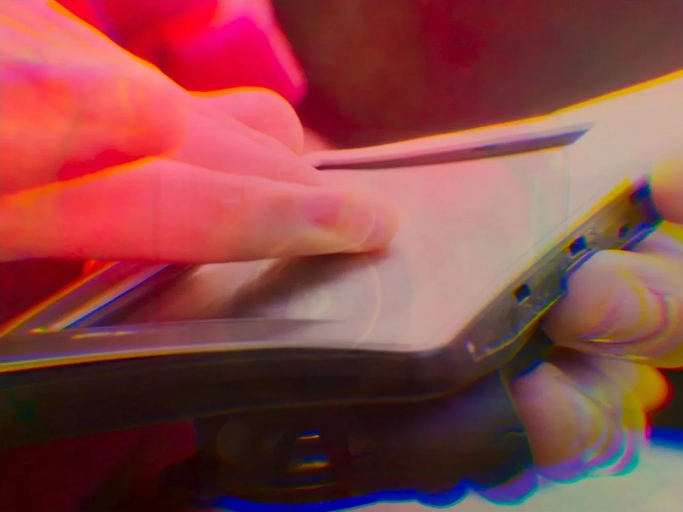 Une personne tient un smartphone en regardant un écran, avec un effet de distorsion colorée.