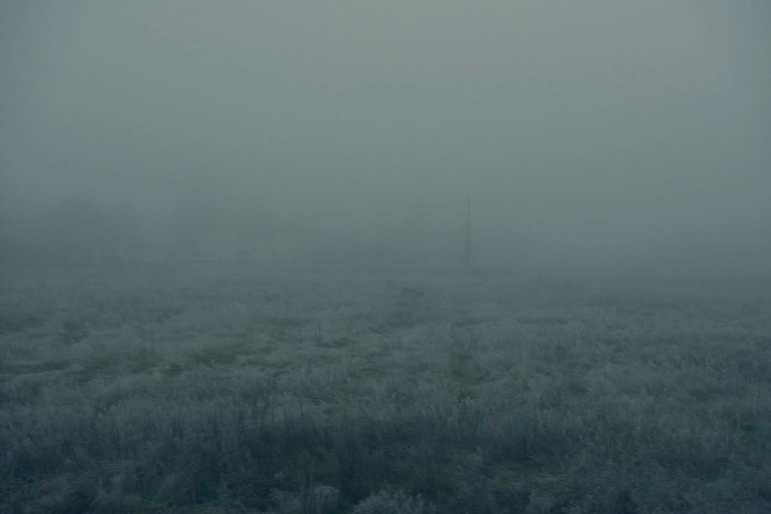 Une mer agitée sous un ciel brumeux avec une visibilité limitée, peu de détails visibles en raison de la brume.