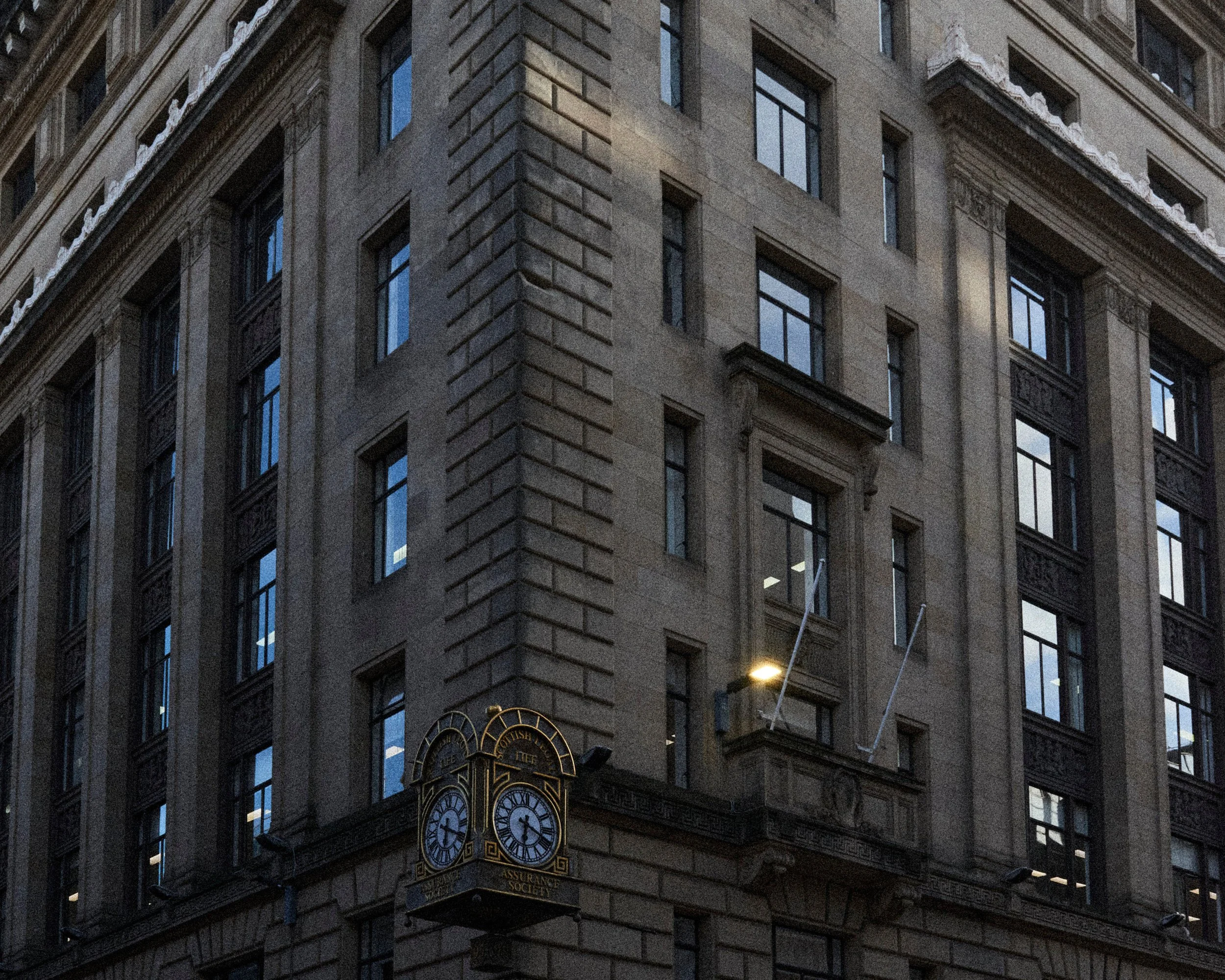 Une façade d'immeuble en pierre avec un horloge et une enseigne indiquant la 'Scottish Insurance Society'.
