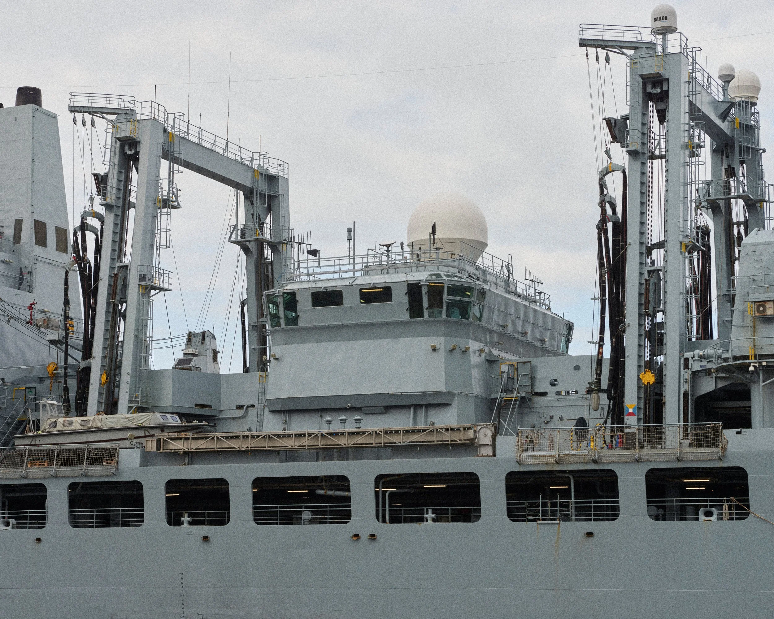Vue partielle d'un porte-avions avec le pont et la superstructure, des radars et des antennes, en mer par un temps nuageux.