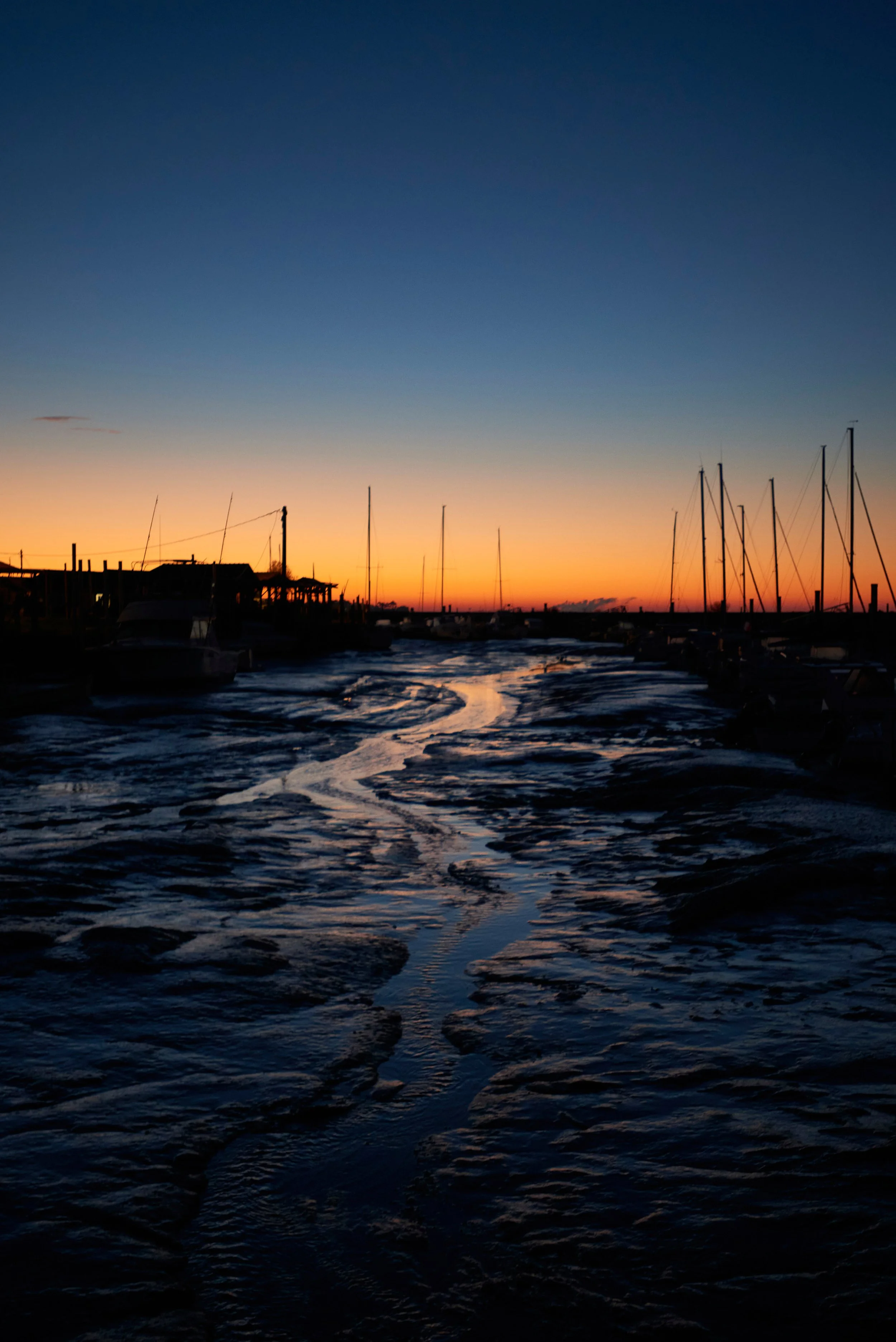 Couchers de soleil sur un port avec des voiliers amarrés et des maisons en silhouette