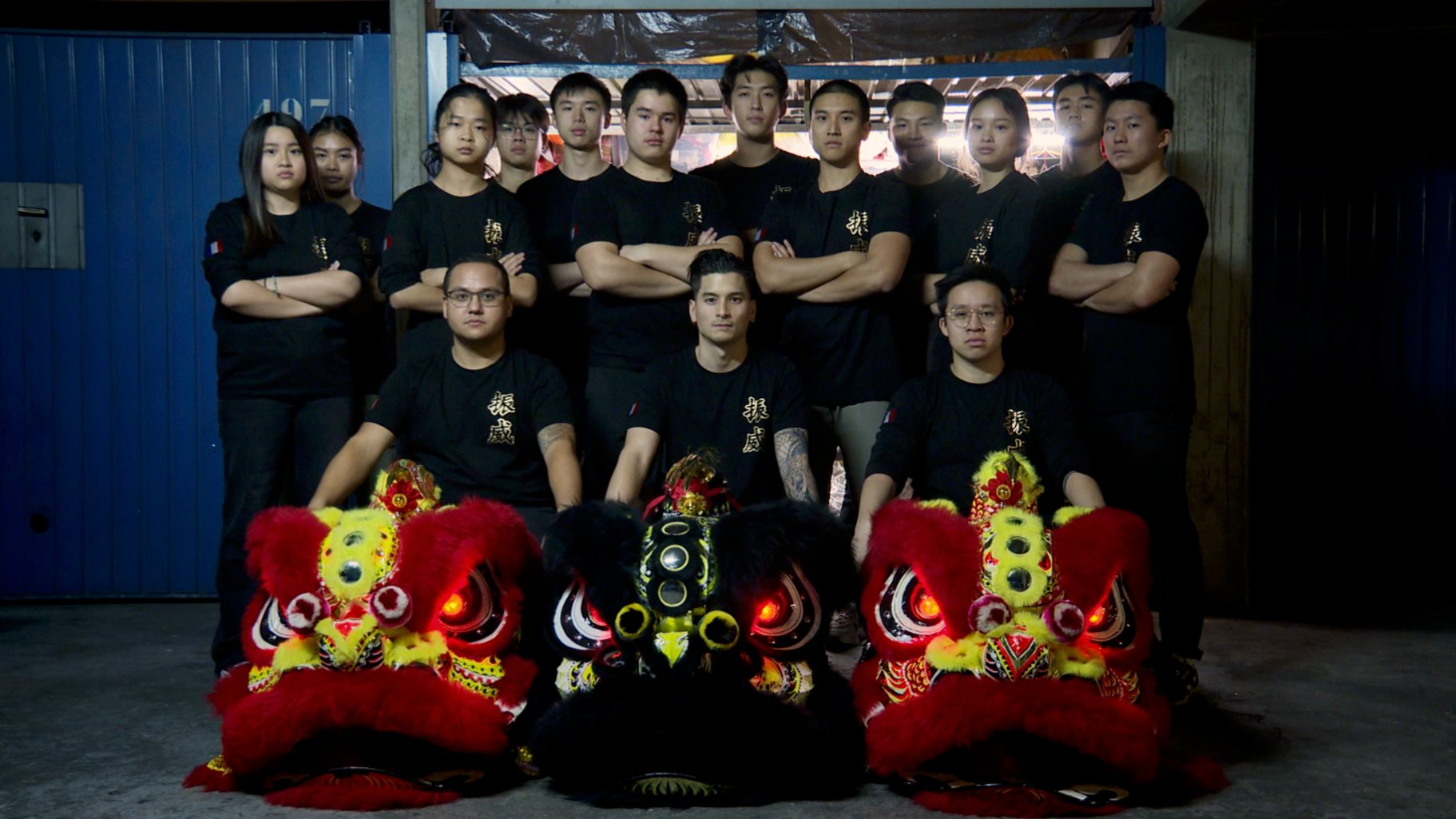 Groupe de jeunes gens en vêtements noirs posant derrière deux lions traditionnels pour une danse lion en Chine.