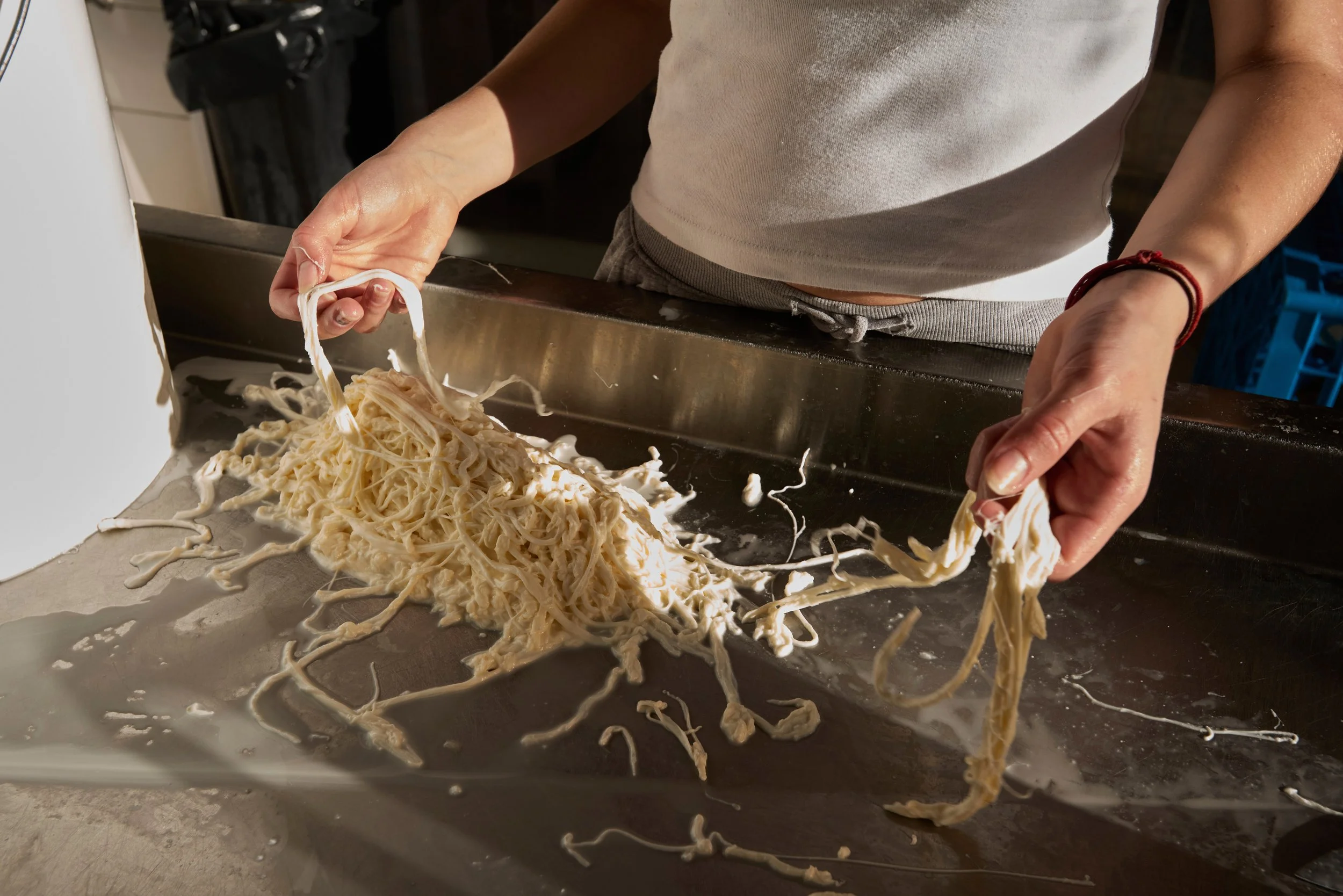 Une personne maniant des pâtes fraîches sur un plan de travail en cuisine.