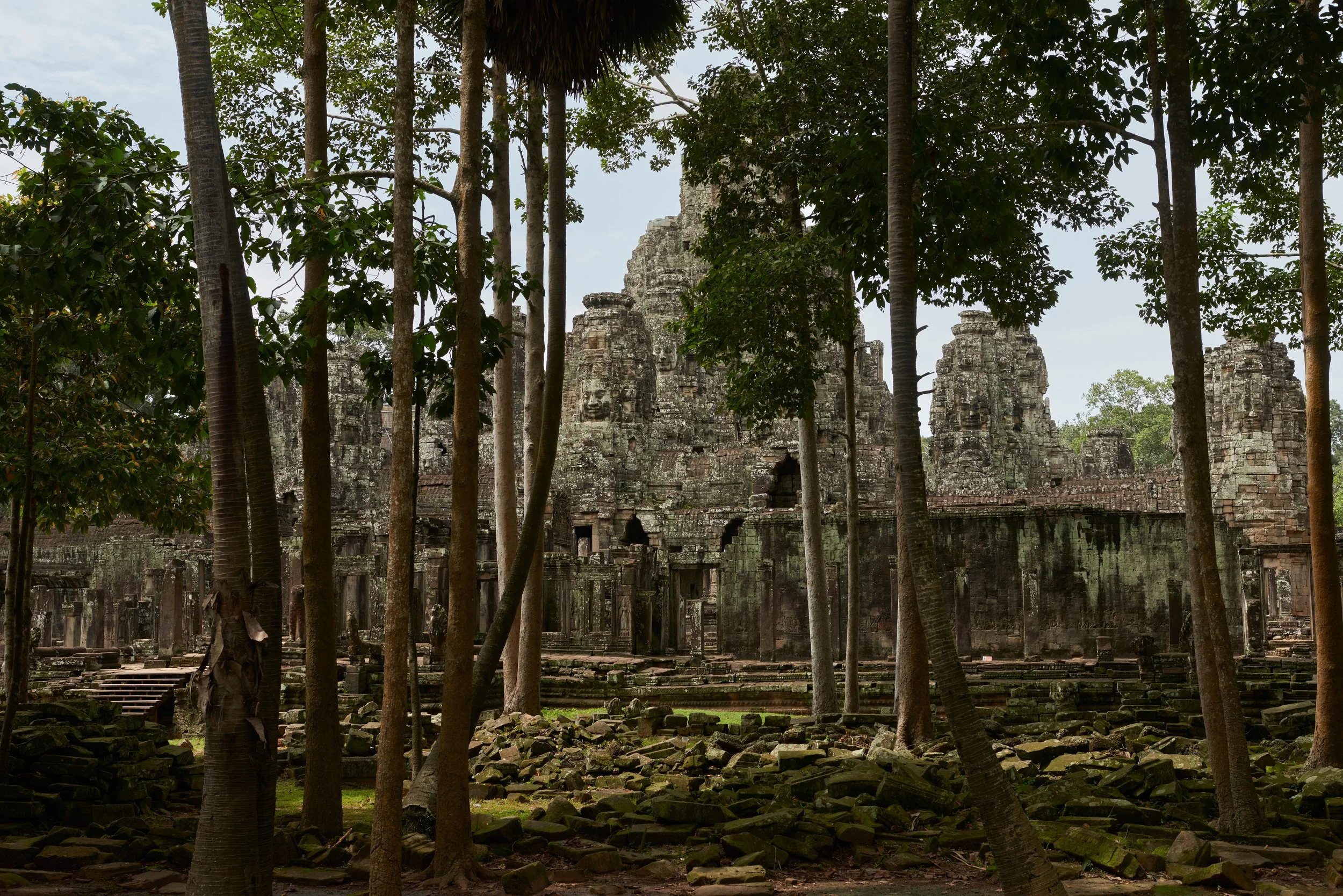 Ruines anciennes de temples entourées d'arbres dans une forêt dense à Angkor, Cambodge.