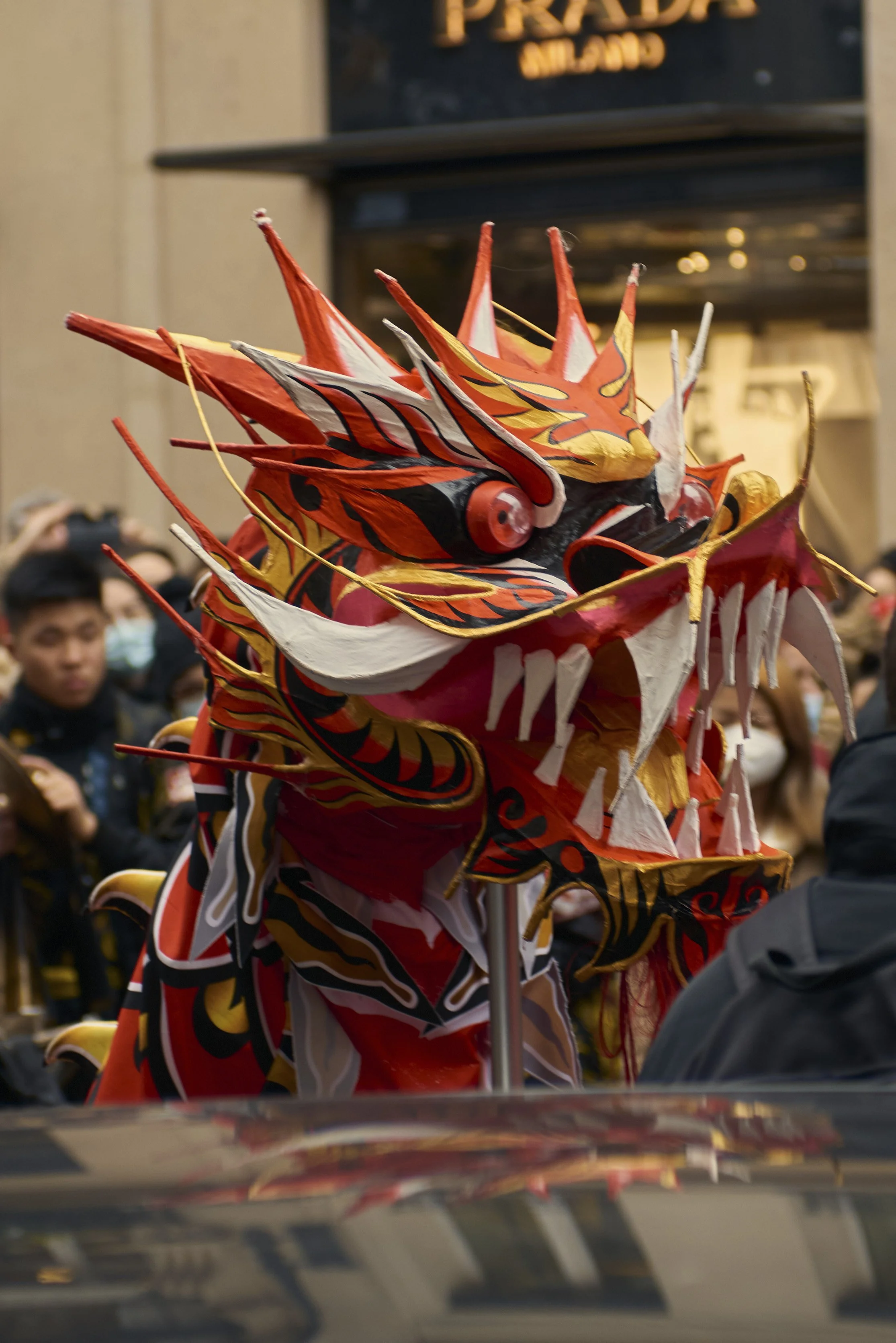 Un danseur en costume de dragon coloré lors d'une parade, avec un public en arrière-plan