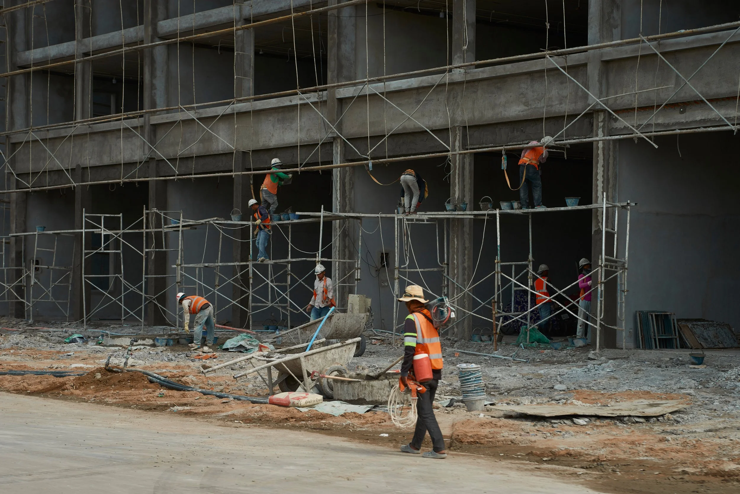 Travaux de construction avec plusieurs ouvriers portant des équipements de sécurité sur un bâtiment en construction.