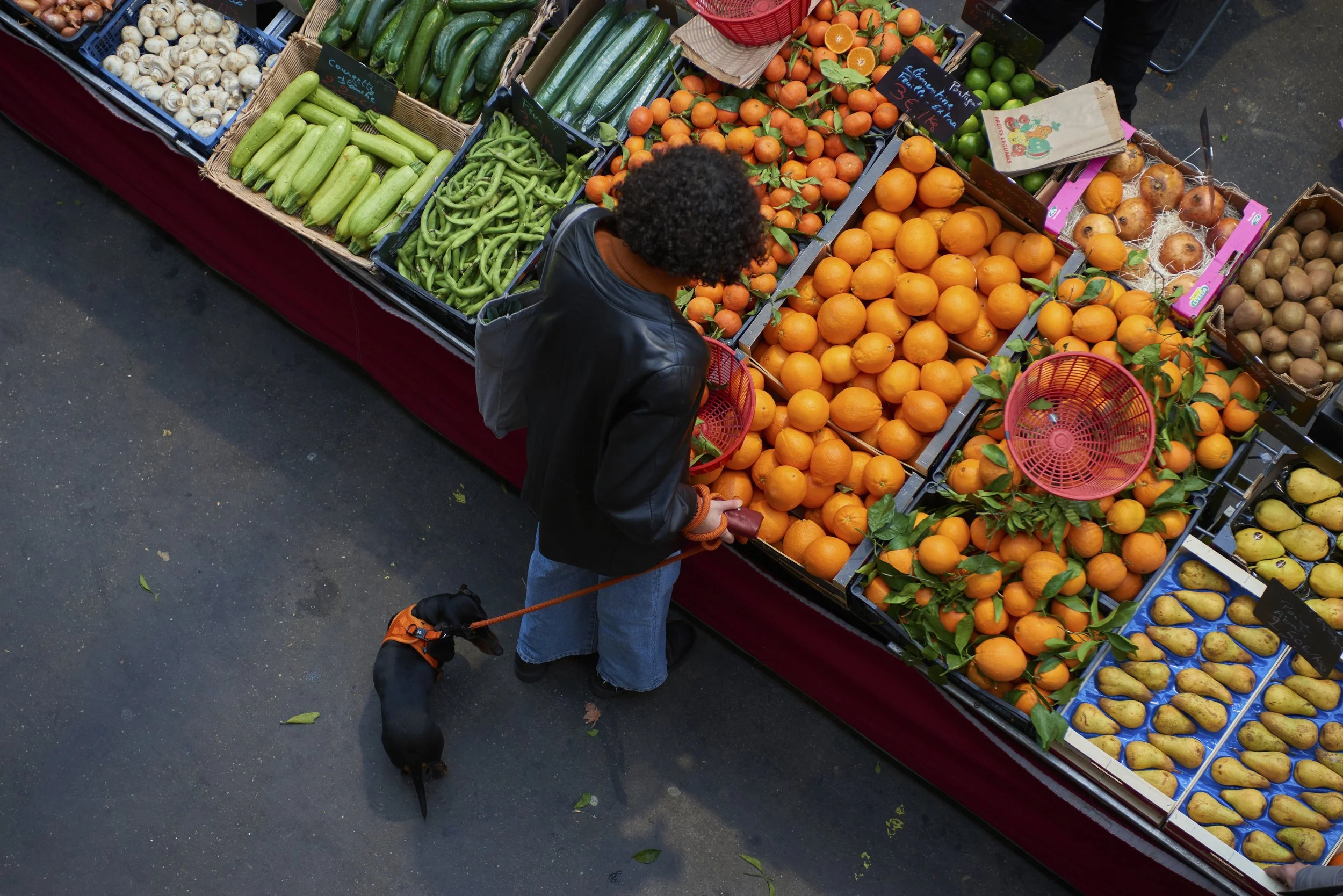 Vue aérienne d'un étal de marché avec des fruits et légumes: courgettes, concombres, clémentines, oranges, pommes de terre et autres.