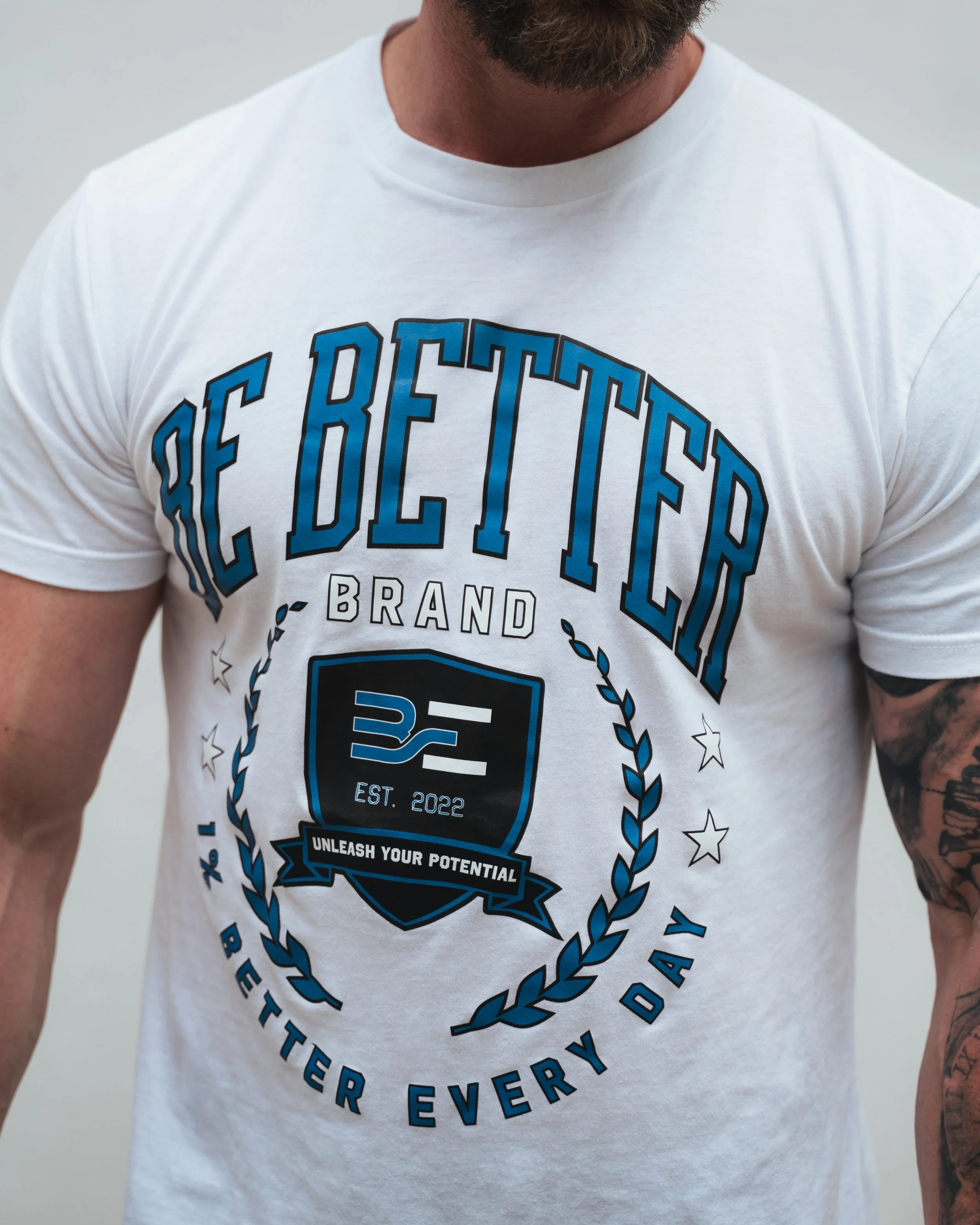 Close-up of a man wearing a white T-shirt with a blue and black graphic design and text that says "Unleash Your Potential."