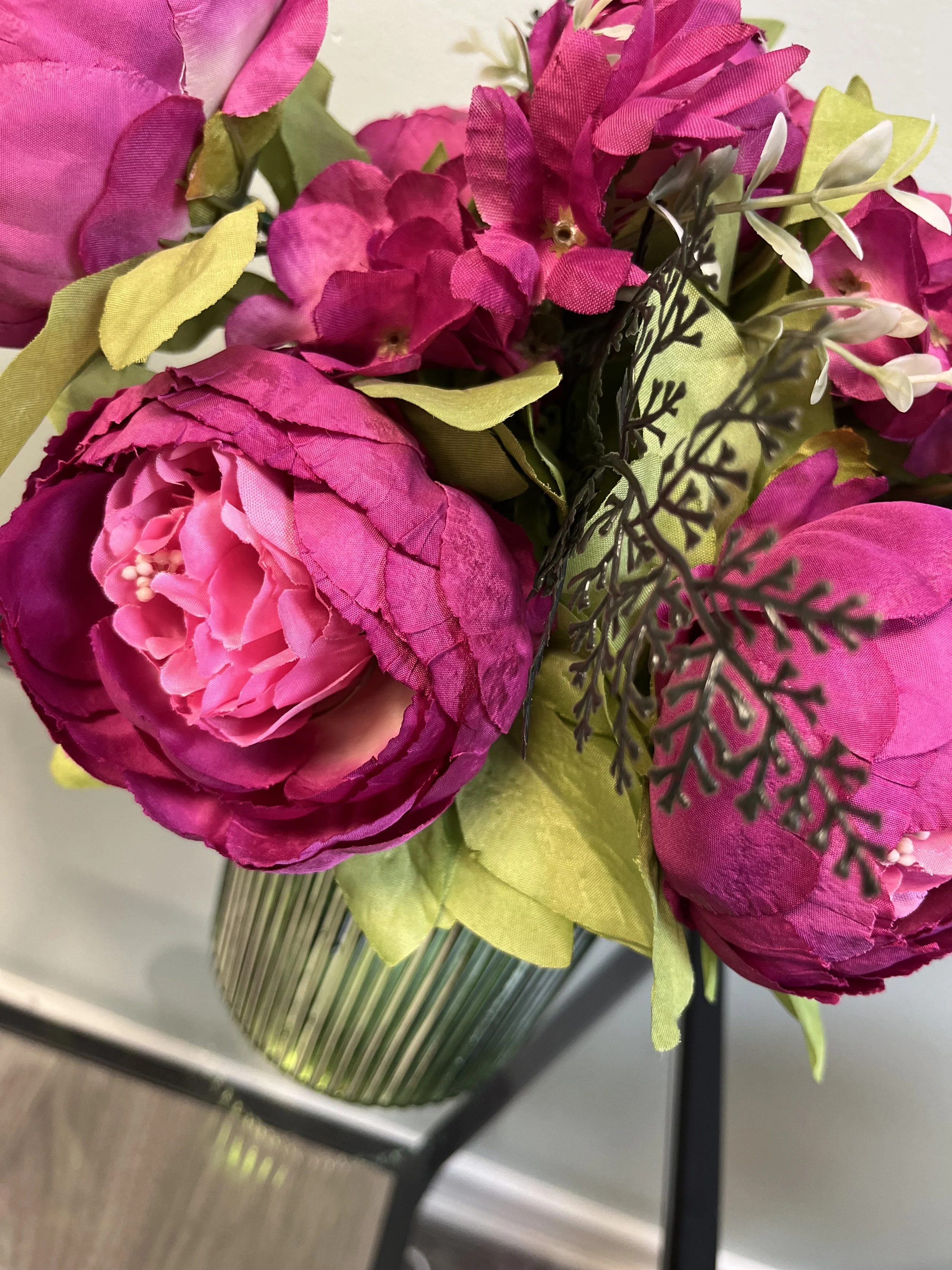 Bouquet of magenta peonies and greenery in a ribbed glass vase at Blossom Wellness Centre
