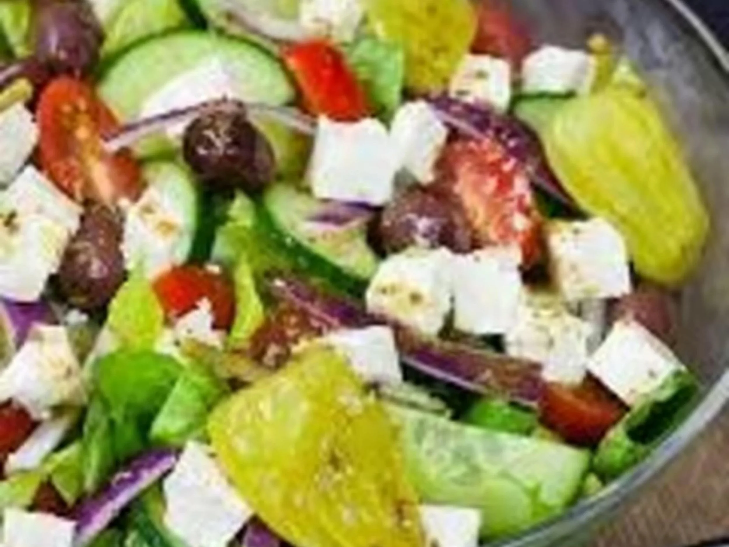 Close-up of a bowl filled with green grapes, strawberries, and sliced white fruit.
