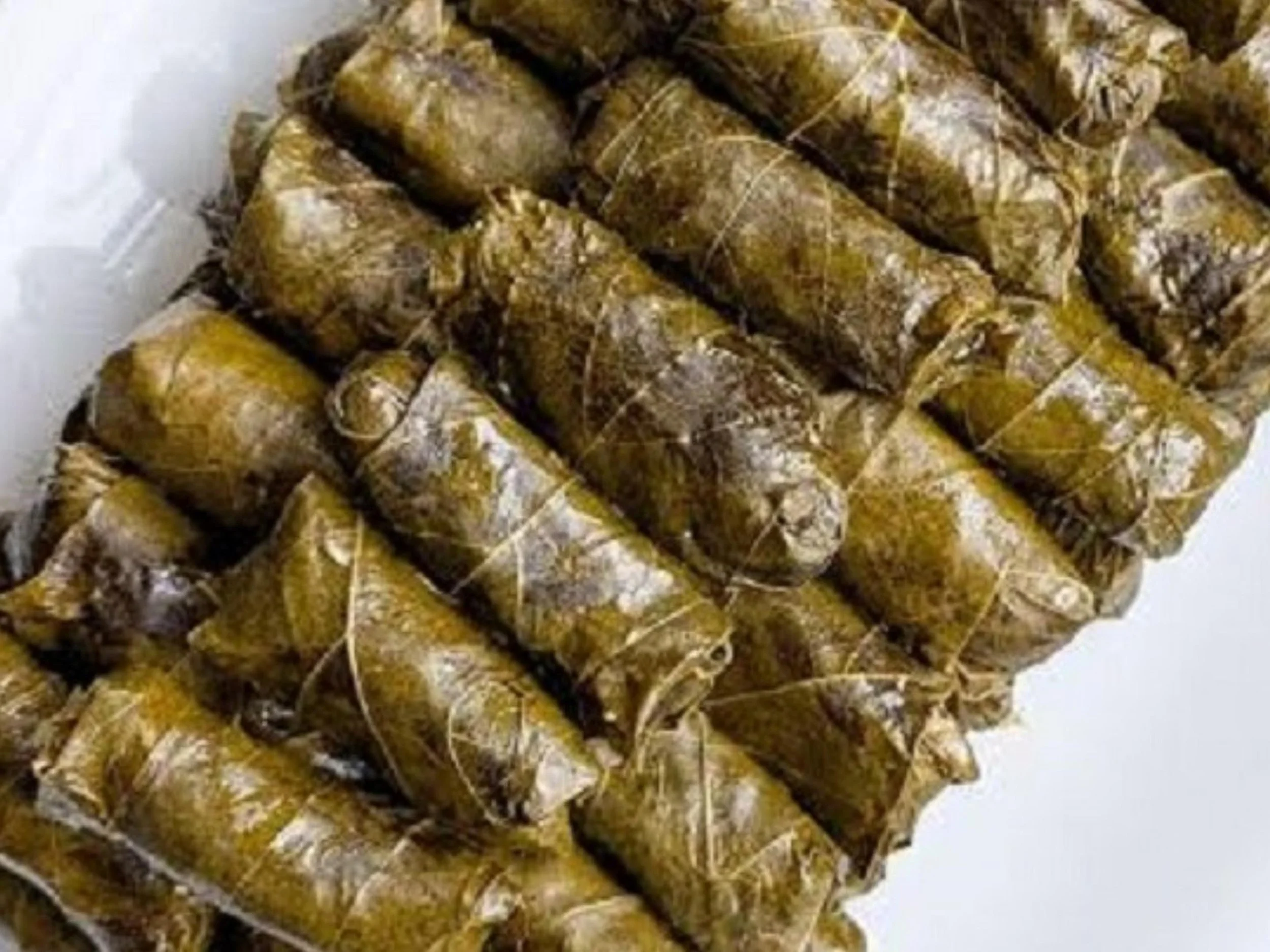 A close-up view of freshly cooked, rolled, and bundled tamales wrapped in corn husks.