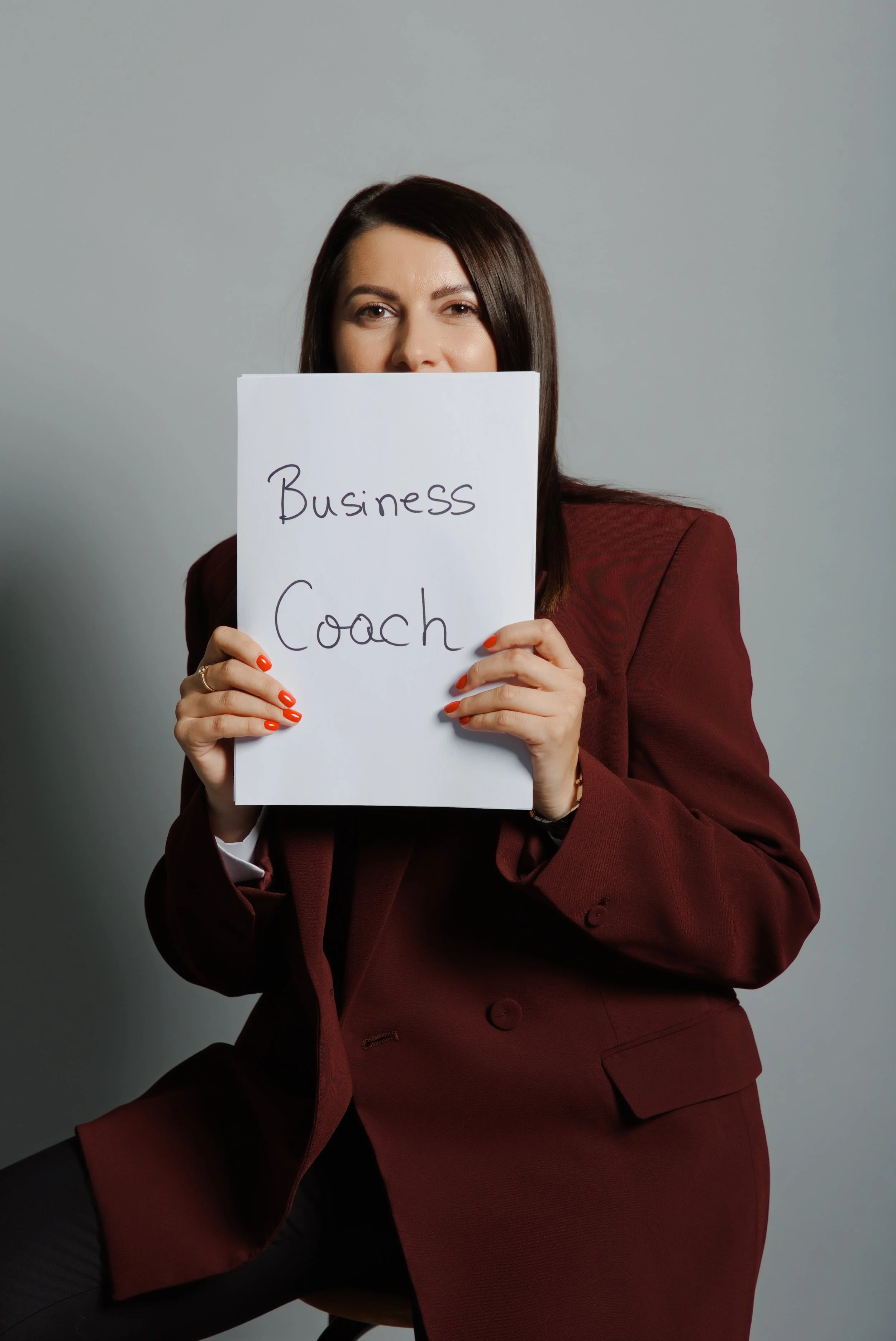 Andreea Crișan ținând un mesaj „Business Coach”, într-o fotografie profesională de branding.