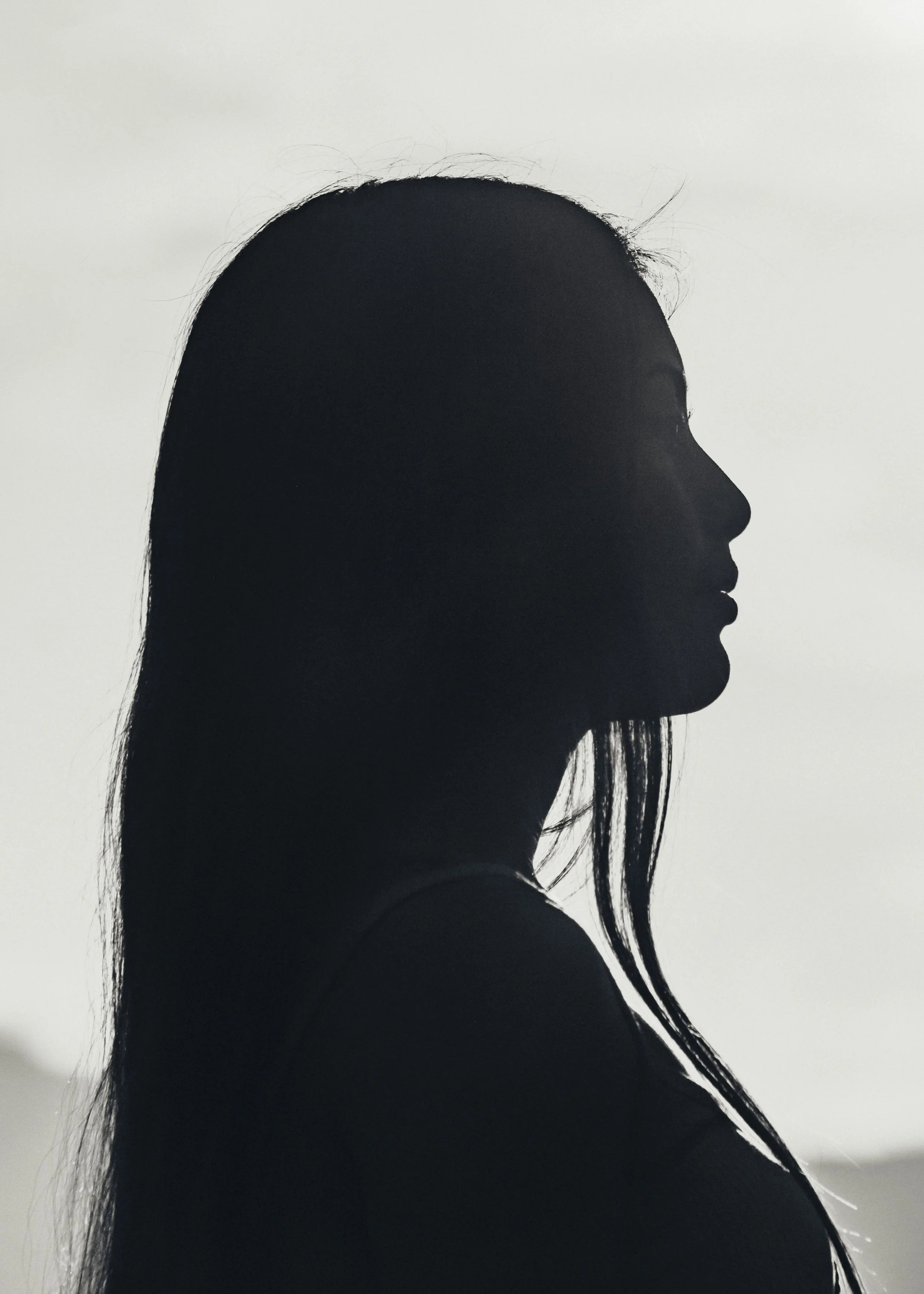 Schwarz-weißer Silhouettenporträt eines Mädchens in Seite, mit langem Haar, vor einem hellen Hintergrund, die über ihren Alltag mit high functioning Burnout berichtet.