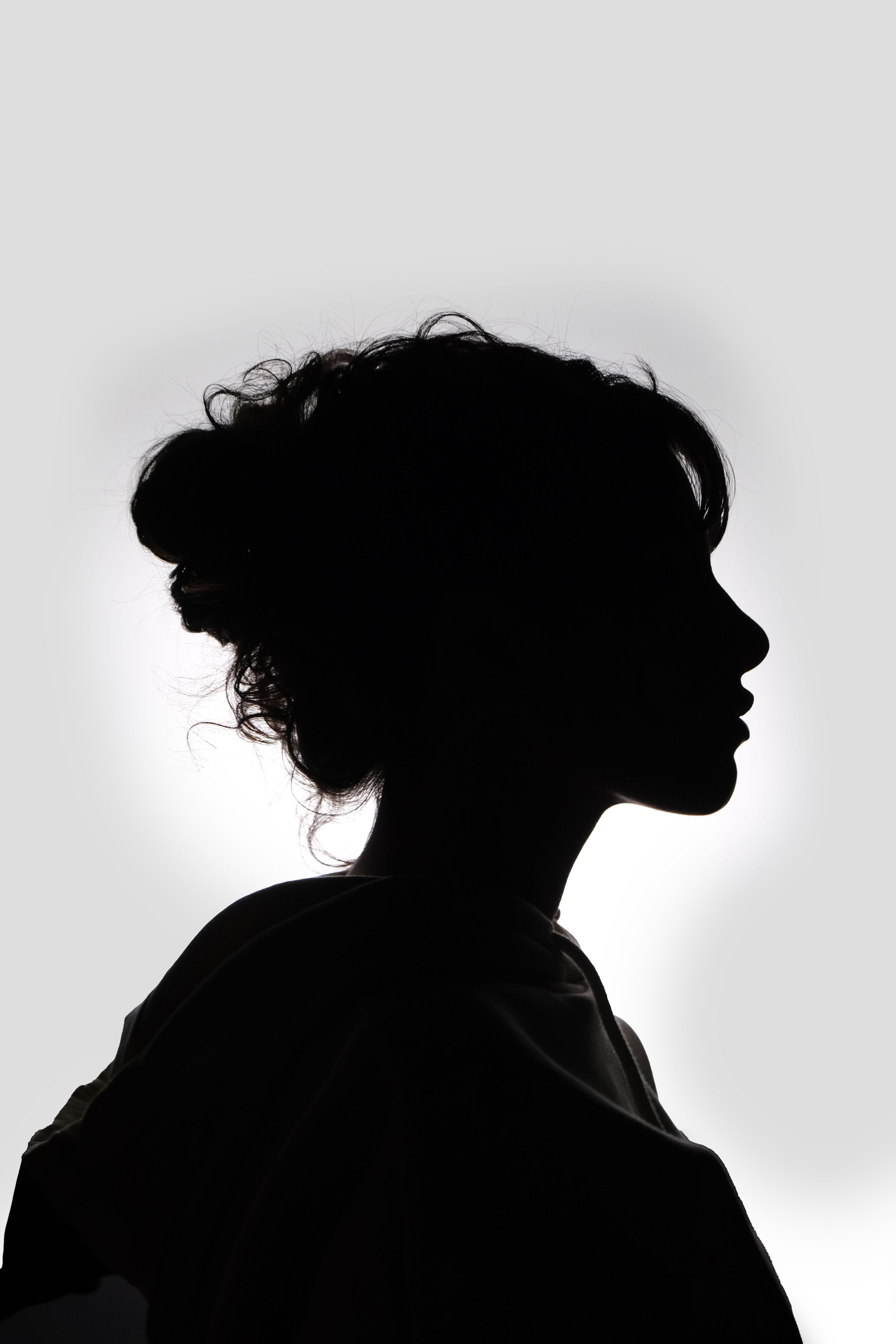 Eine Silhouette einer Frau mit aufgerollten Haaren vor einem hellen Hintergrund, die über ihren Burnout berichtet.