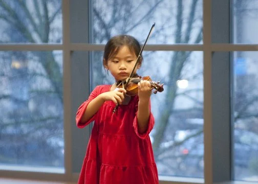 Young child playing the violin in a concert