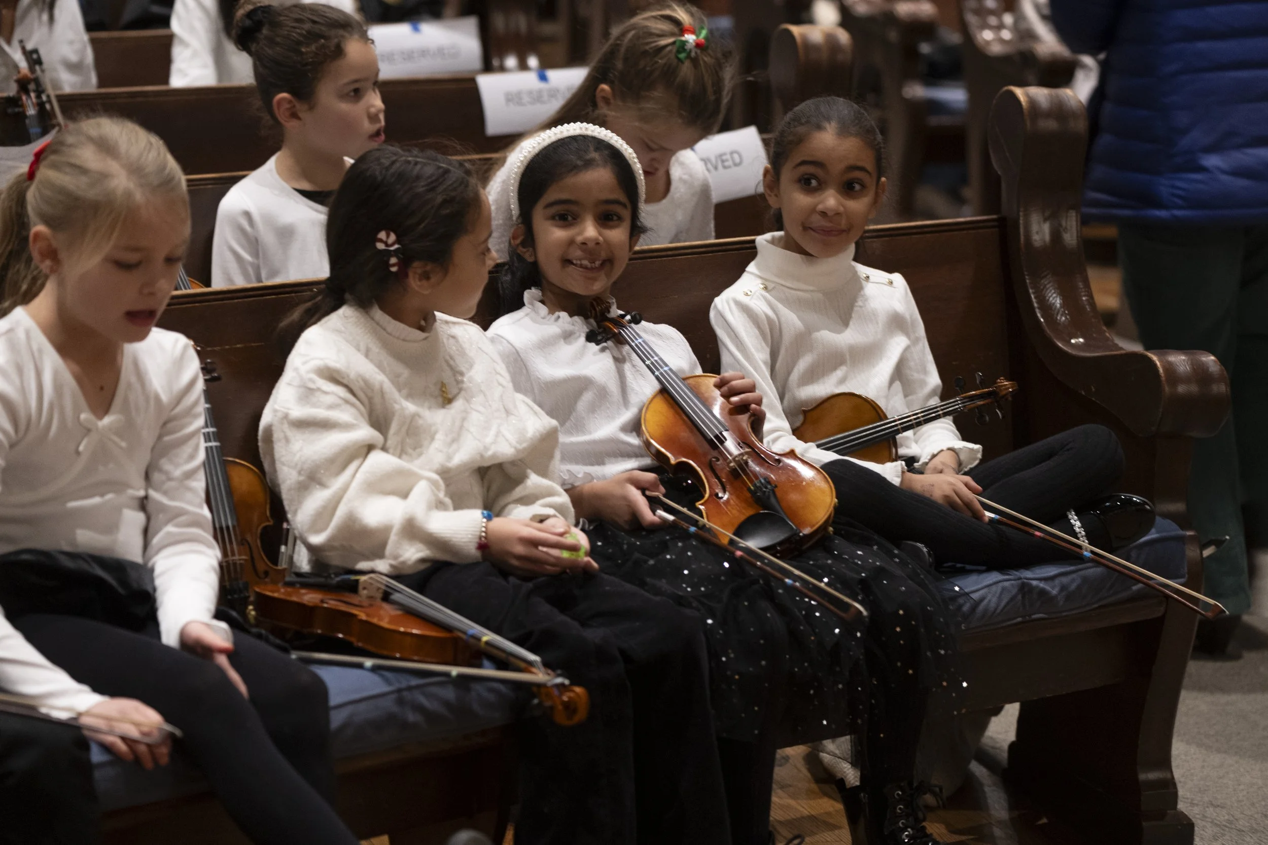 A young student smiling with her violin at a recital
