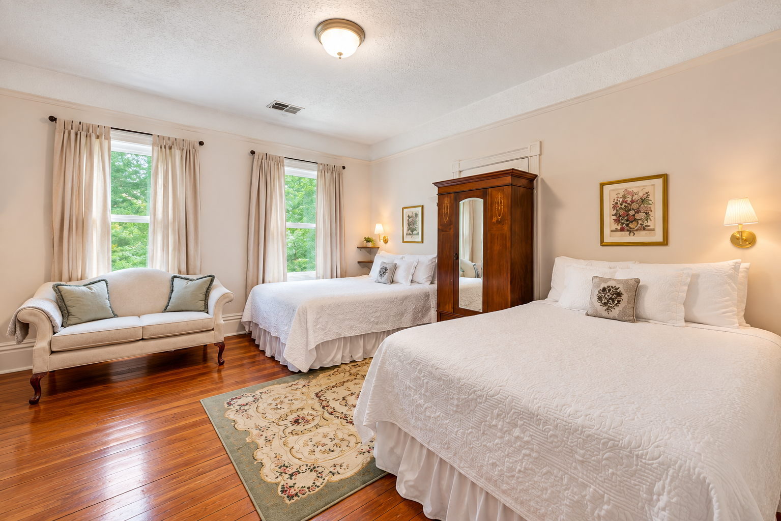A bedroom with two beds, a vintage sofa, windows with beige curtains, hardwood floors, and floral artwork.