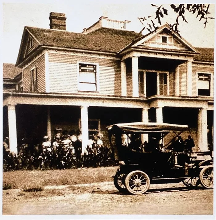 Early photograph of The Veranda Historic Inn in Senoia, Georgia, with guests on the porch and a vintage automobile outside.