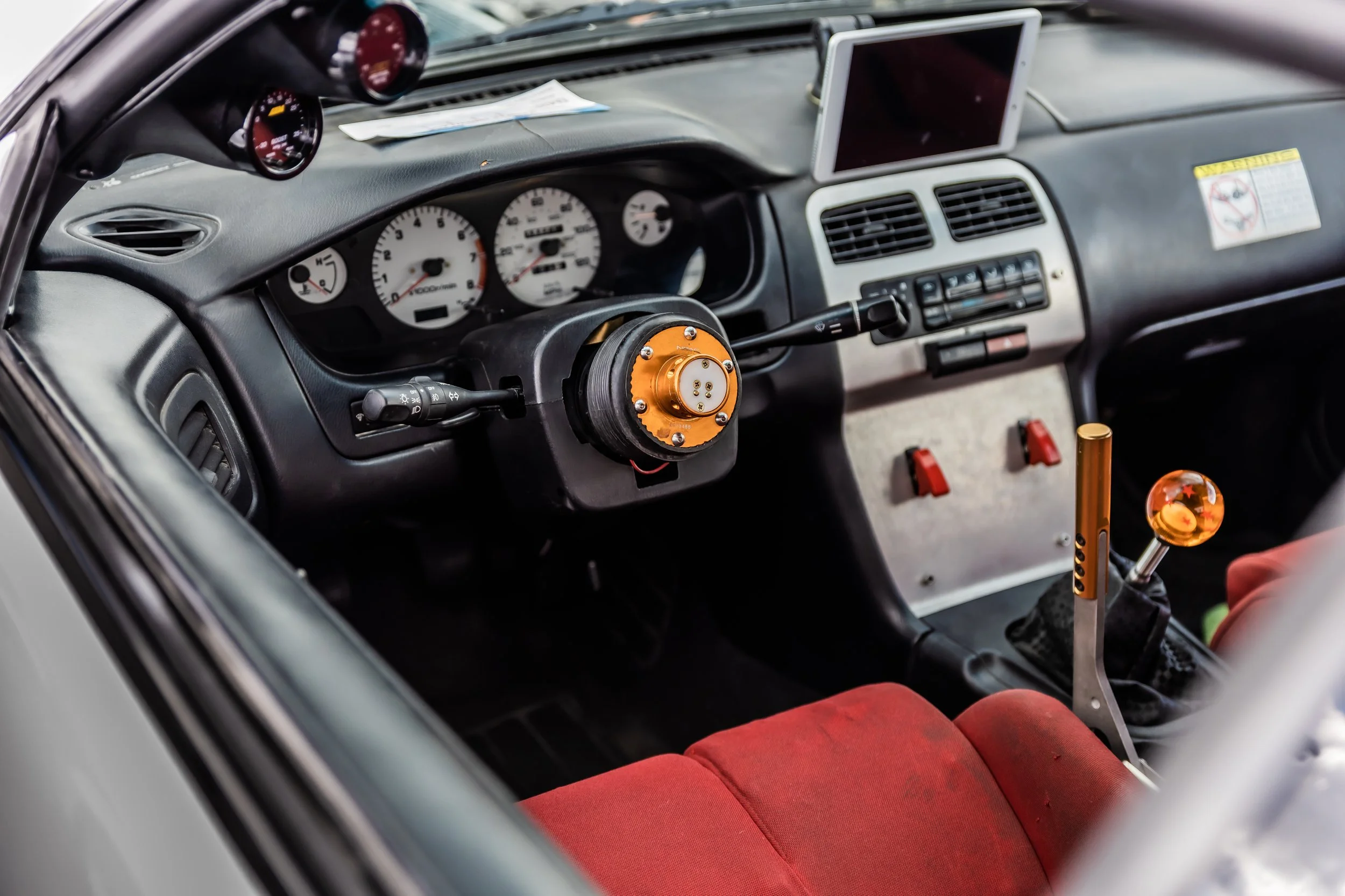 Interior of a car showing the dashboard, gauges, steering wheel, and red seats.