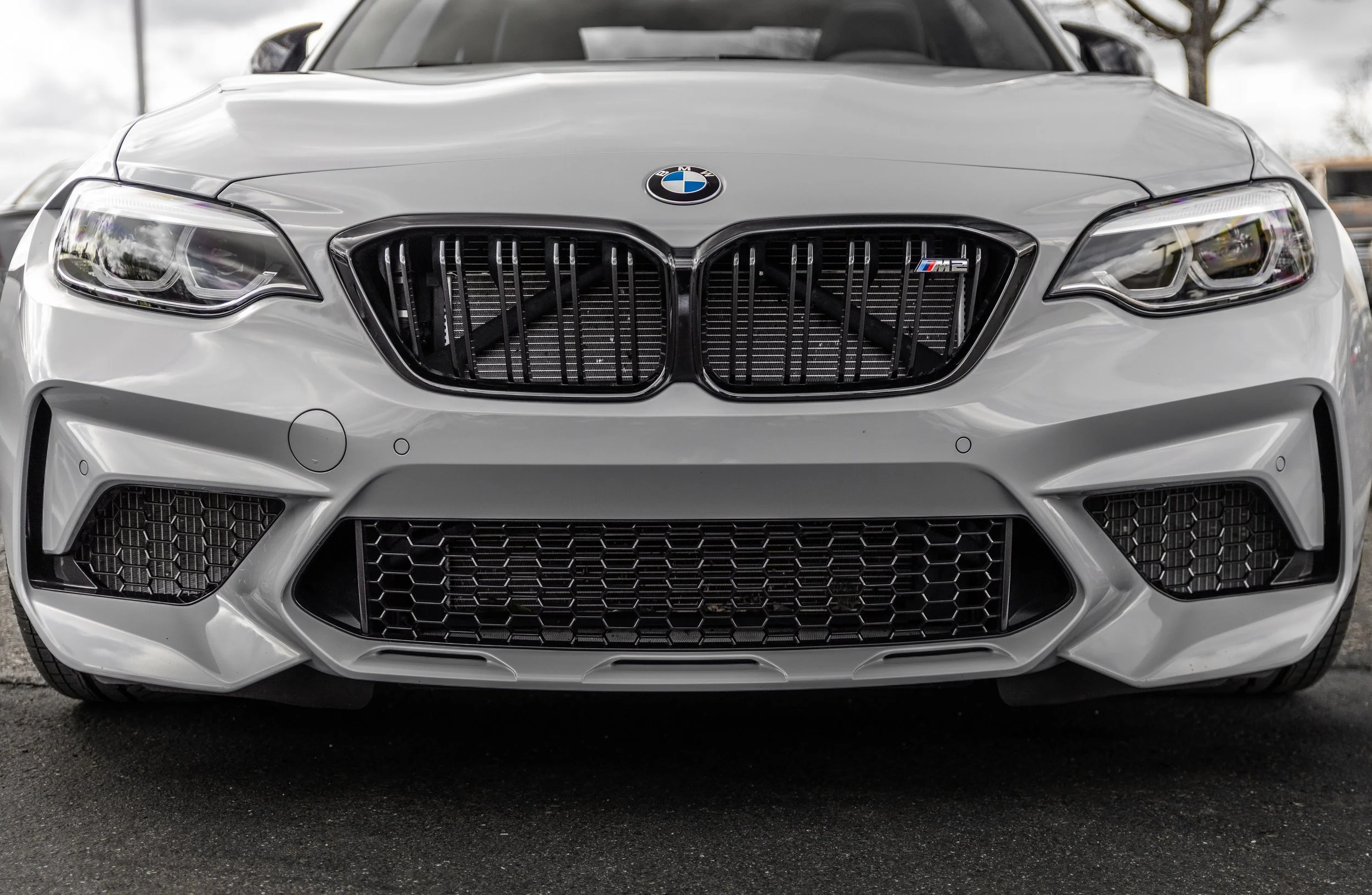 Front view of a white BMW M2 sports car, showing the grille, headlights, and bumper.