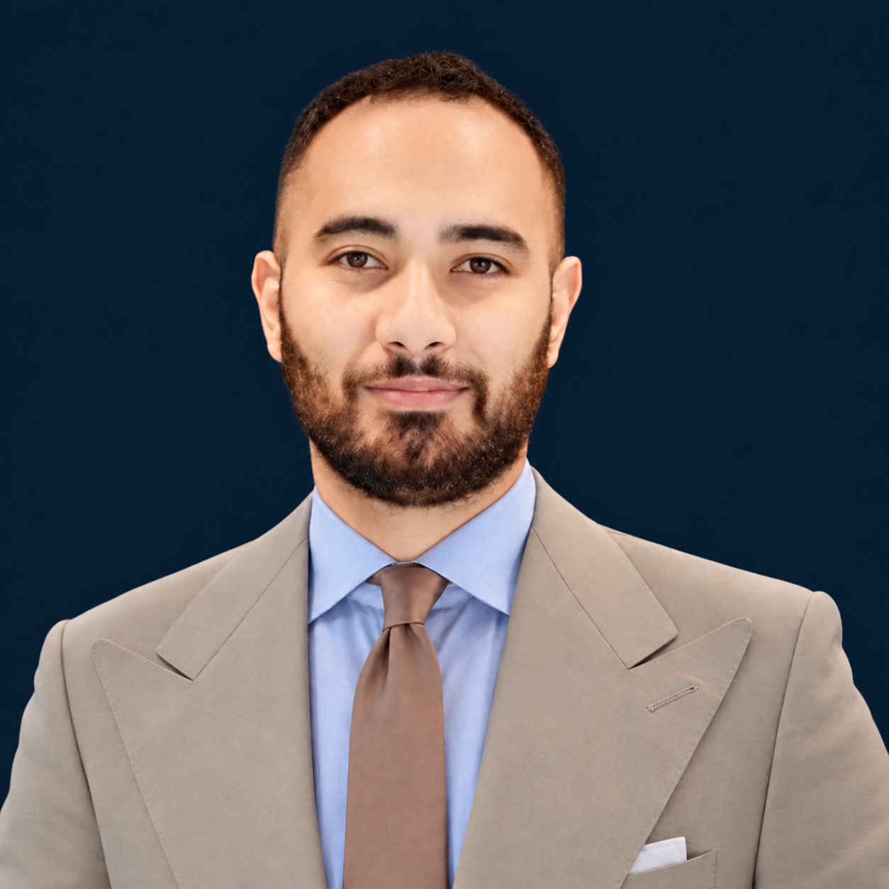 Douglas Kahluhiokalani, Chief Operating Officer at CyberRST, professional headshot in a tan suit with light blue shirt and brown tie