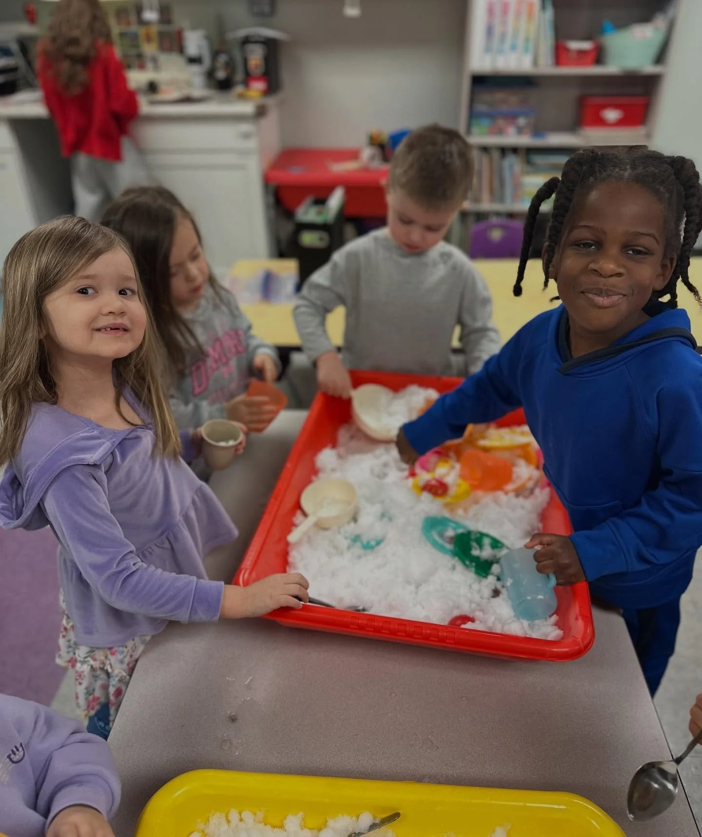 Children playing with snow-like substance in a classroom or playroom setting.