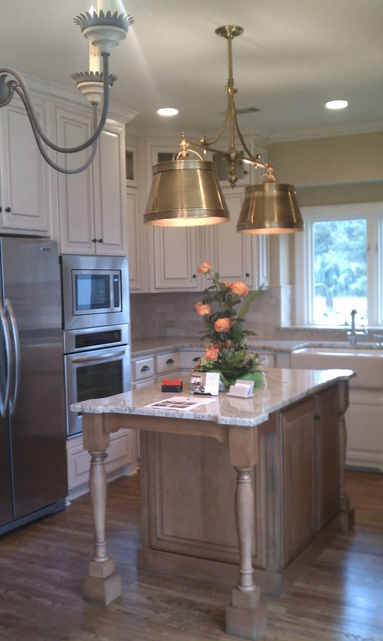Kitchen island with metal dome pendant lights, wood cabinetry, and stainless appliances designed by Bonnie Boyette Designs