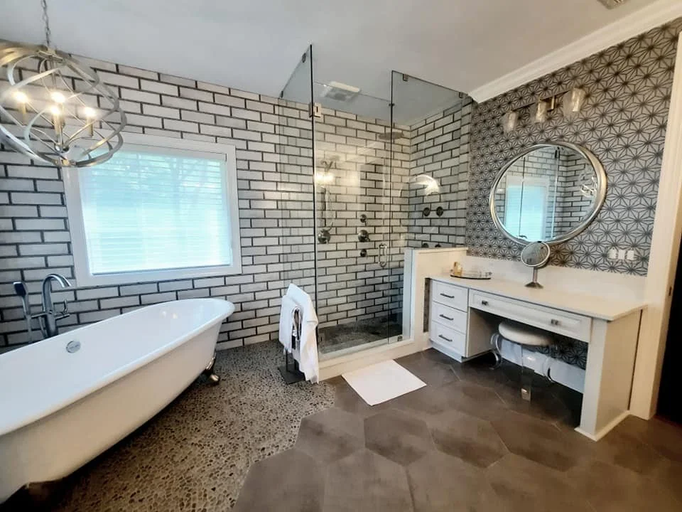 Primary bathroom with gray subway tile, freestanding clawfoot tub, and white vanity designed by Bonnie Boyette Designs