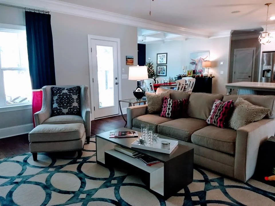Family room with a neutral sofa, navy drapes, and a teal geometric area rug designed by Bonnie Boyette Designs