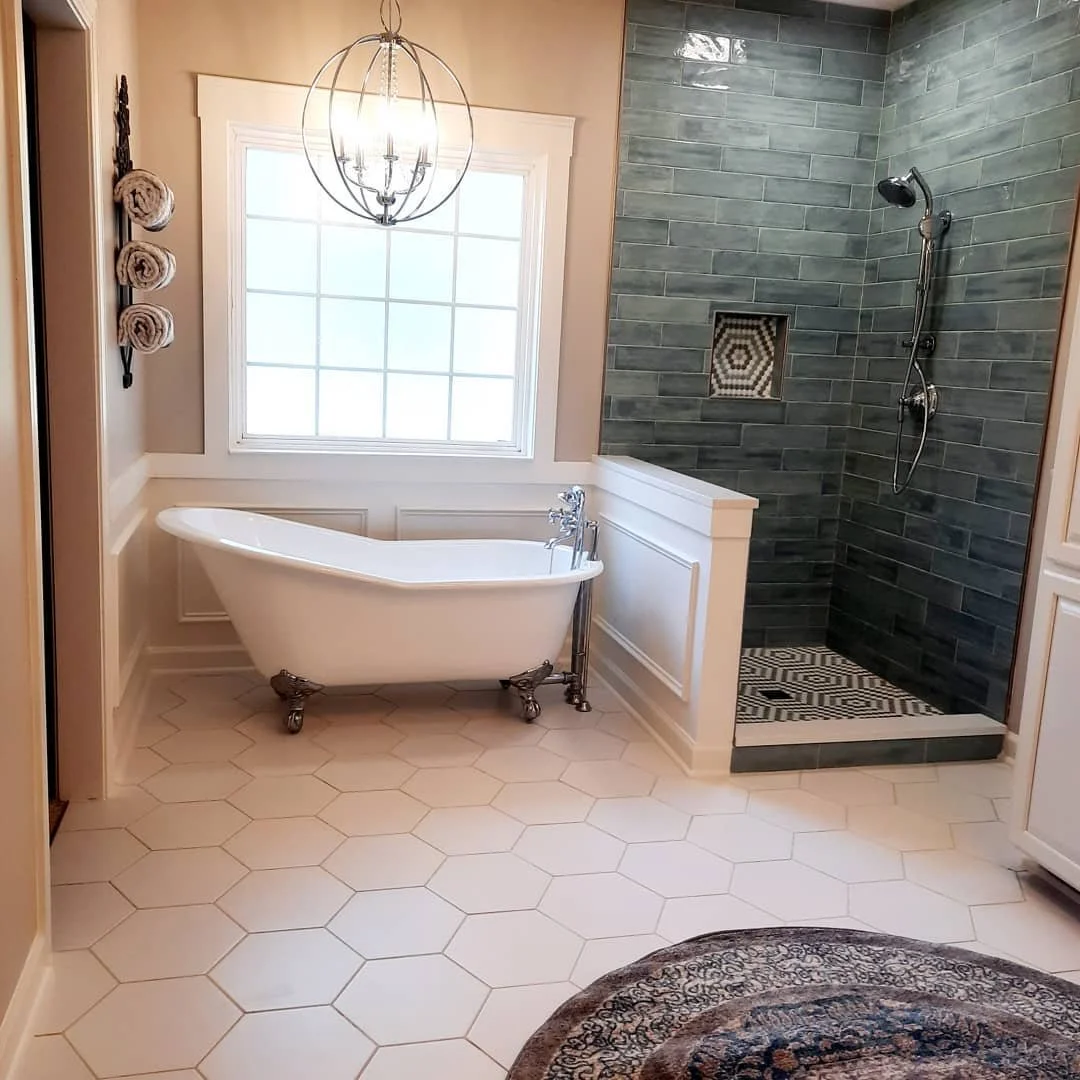 Bathroom with a clawfoot tub beneath a window and a dark tile walk-in shower designed by Bonnie Boyette Designs