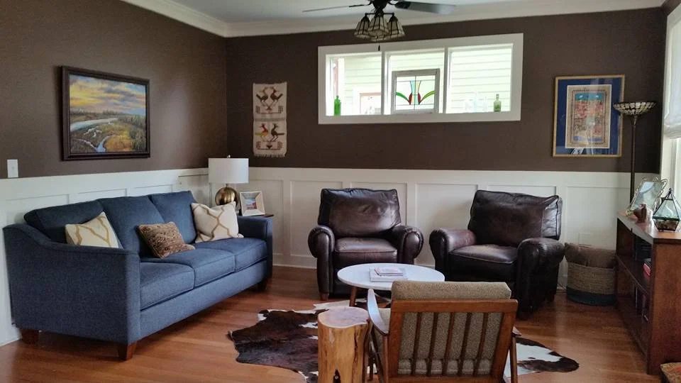 Den with brown walls, a blue sofa, leather club chairs, and a cowhide rug designed by Bonnie Boyette Designs
