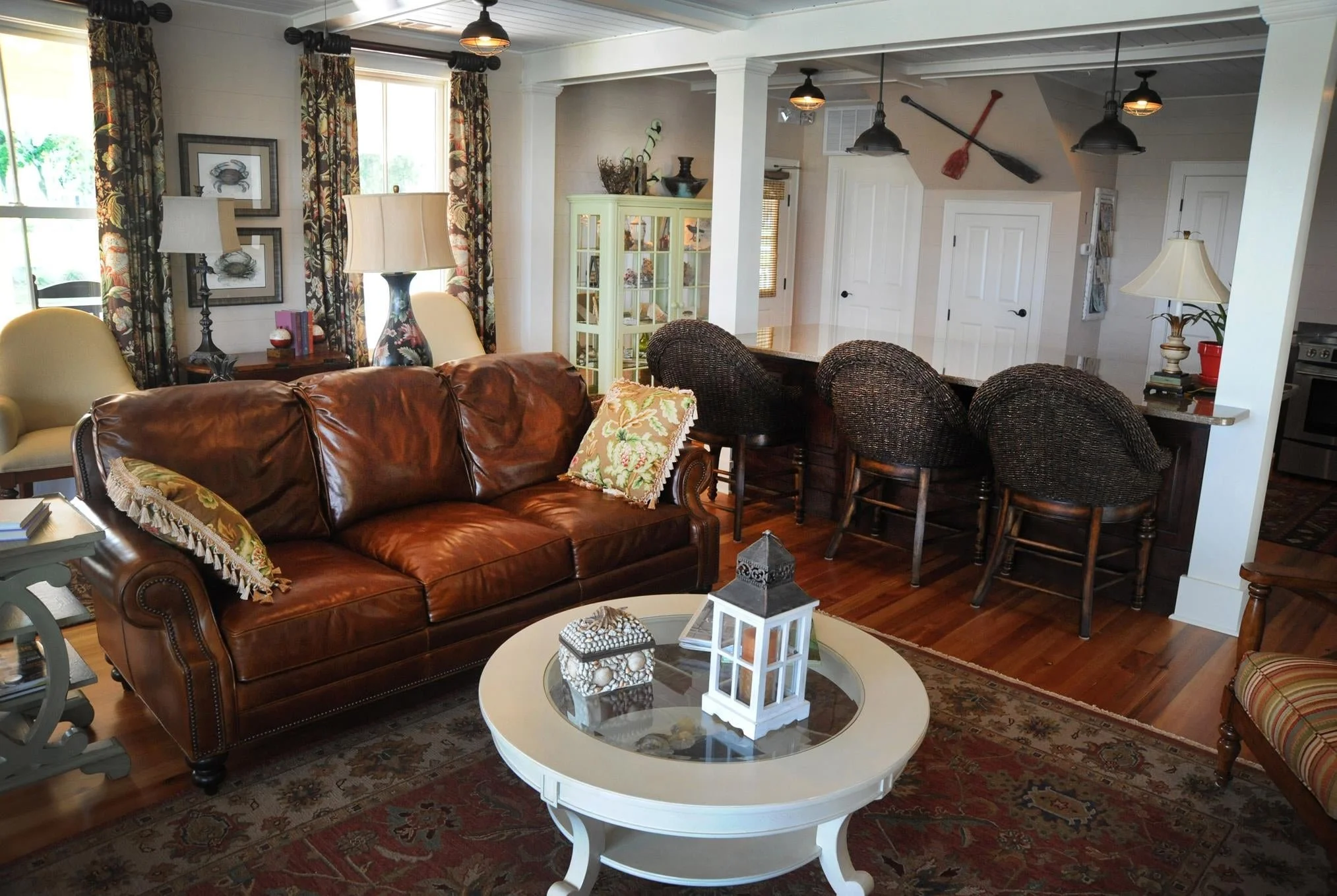 Living room with a brown leather sofa, round white coffee table, and patterned rug designed by Bonnie Boyette Designs