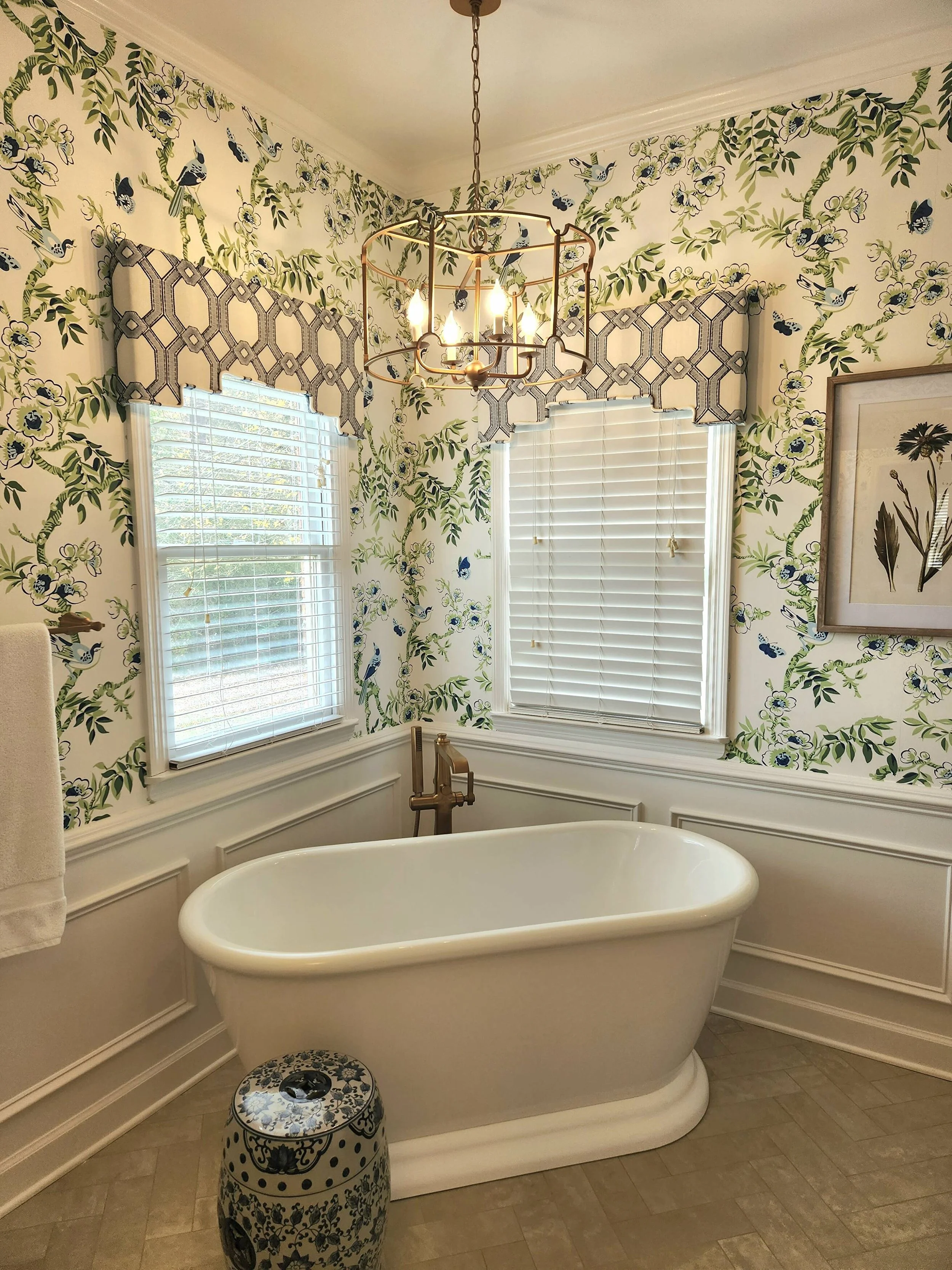 Bathroom with a freestanding soaking tub, floral wallpaper, and plantation shutters designed by Bonnie Boyette Designs