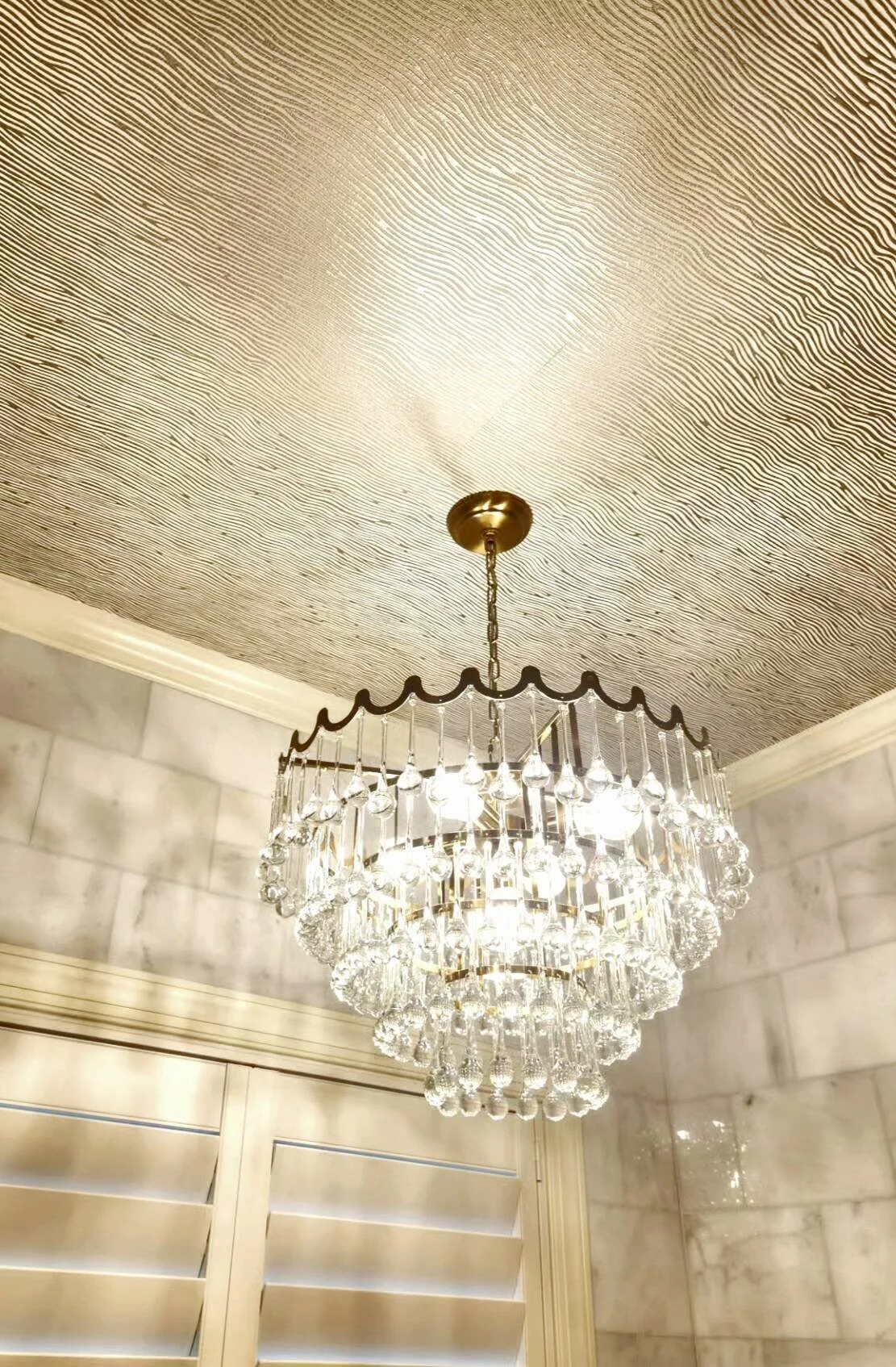 Crystal chandelier under a textured metallic wallpapered ceiling, lighting design by Bonnie Boyette Designs