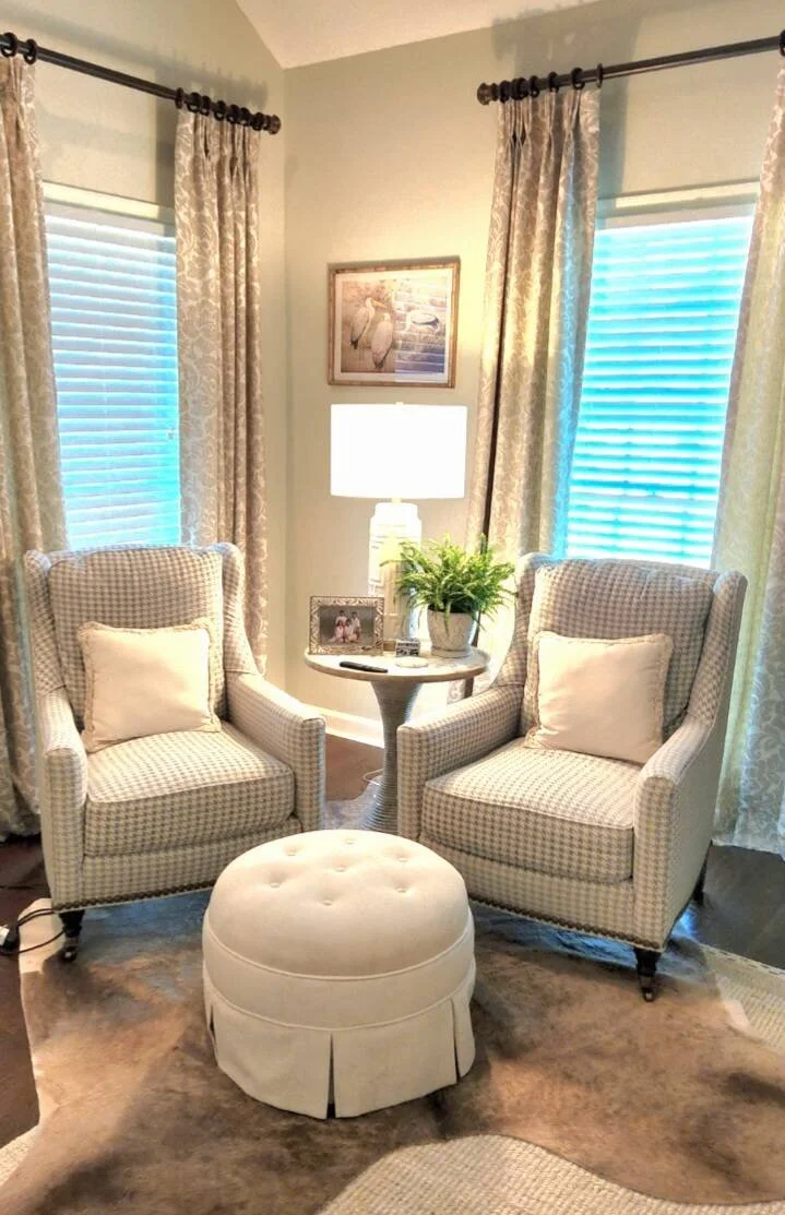 Bay window seating area with two upholstered armchairs and a tufted ottoman designed by Bonnie Boyette Designs