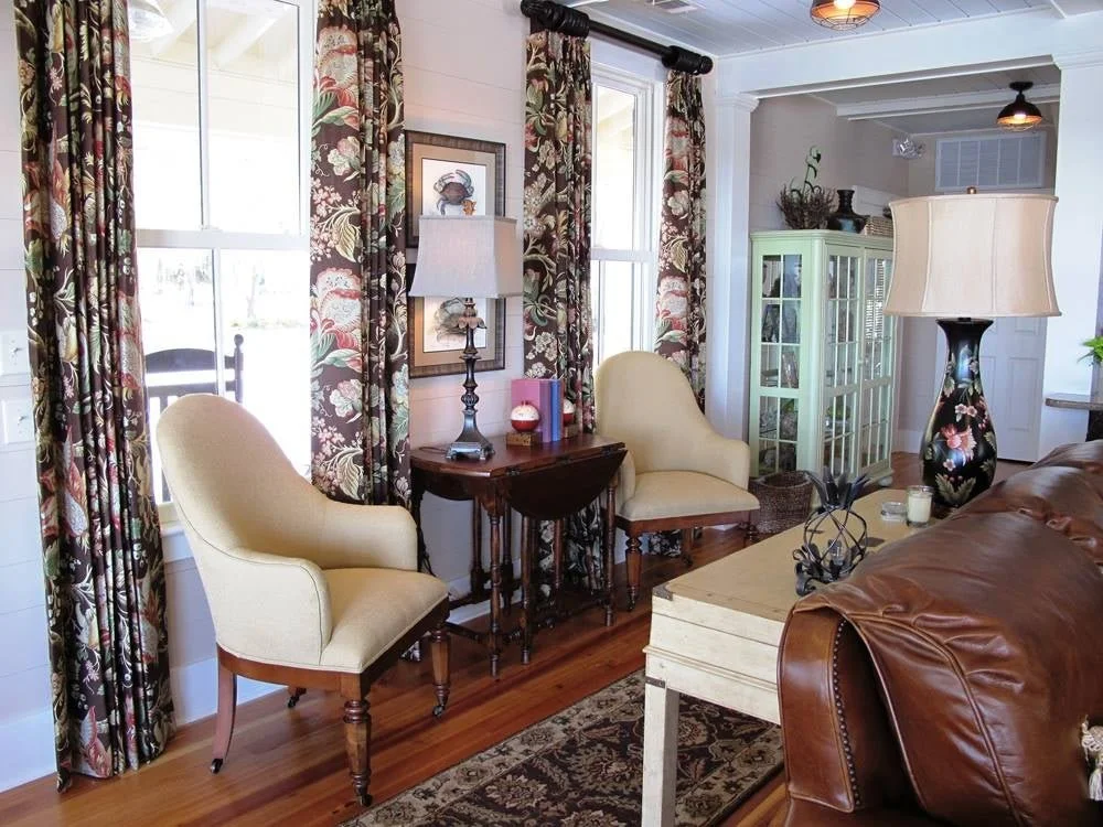 Sitting room with cream upholstered chairs, floral drapery, and a leather sofa designed by Bonnie Boyette Designs