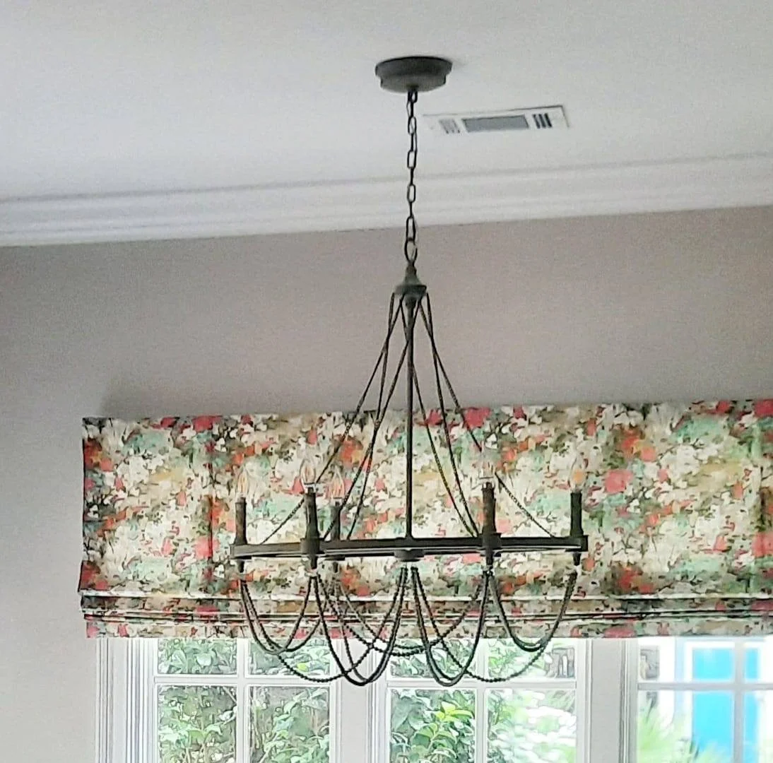 Wrought iron chandelier in front of a floral Roman shade and window valance designed by Bonnie Boyette Designs