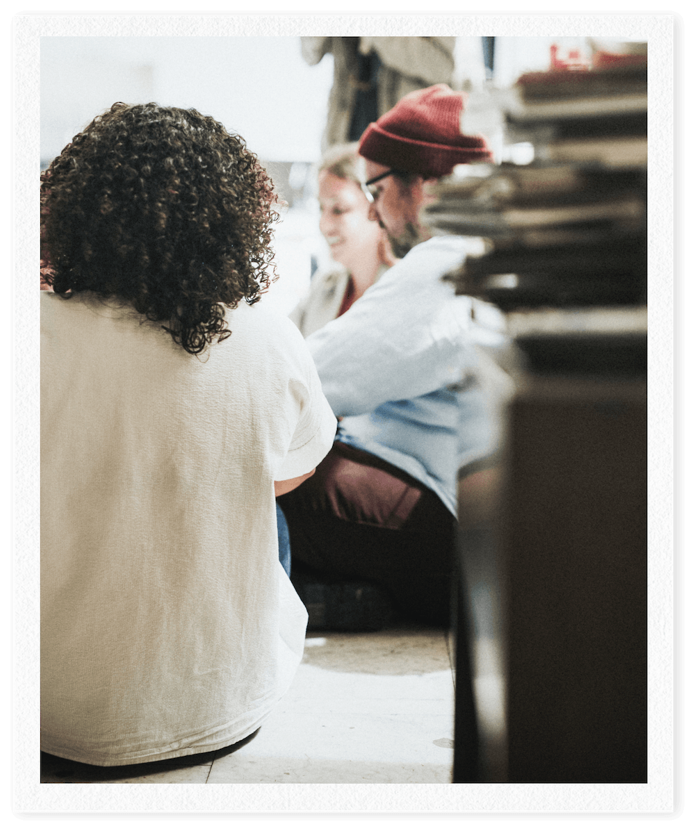 People sitting on the floor and engaging in conversation, with a stack of papers or files nearby.
