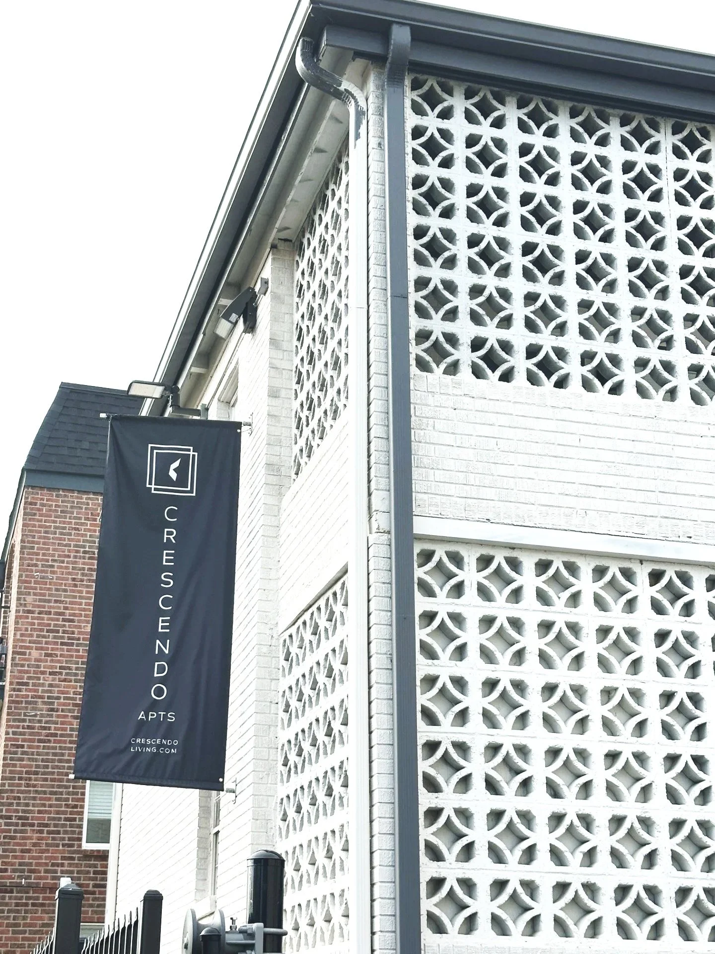 Exterior of a building with white decorative concrete blocks and a black banner reading 'Crescendo Living.'