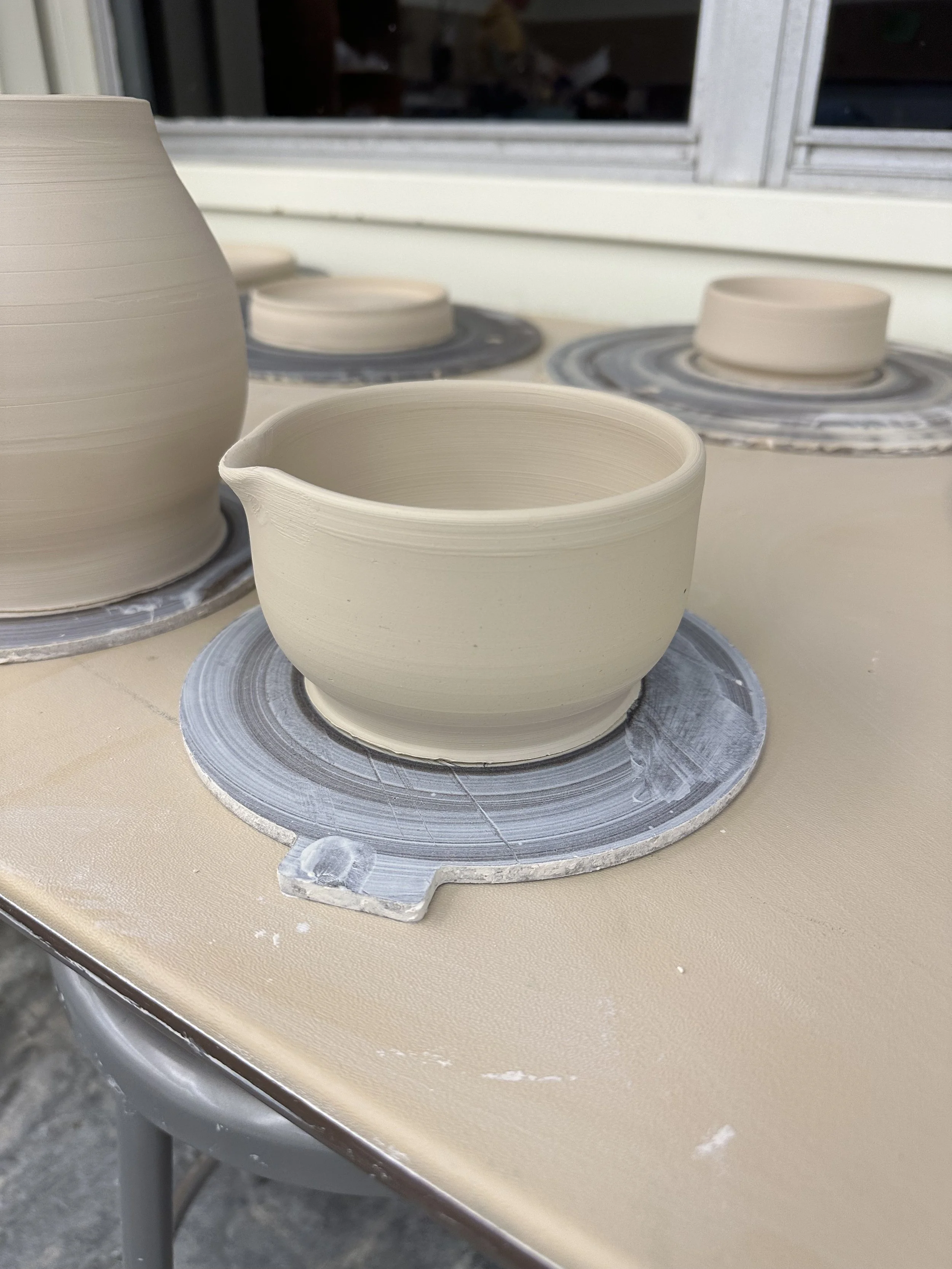 Unfinished pottery bowls on pottery wheels in a workshop.