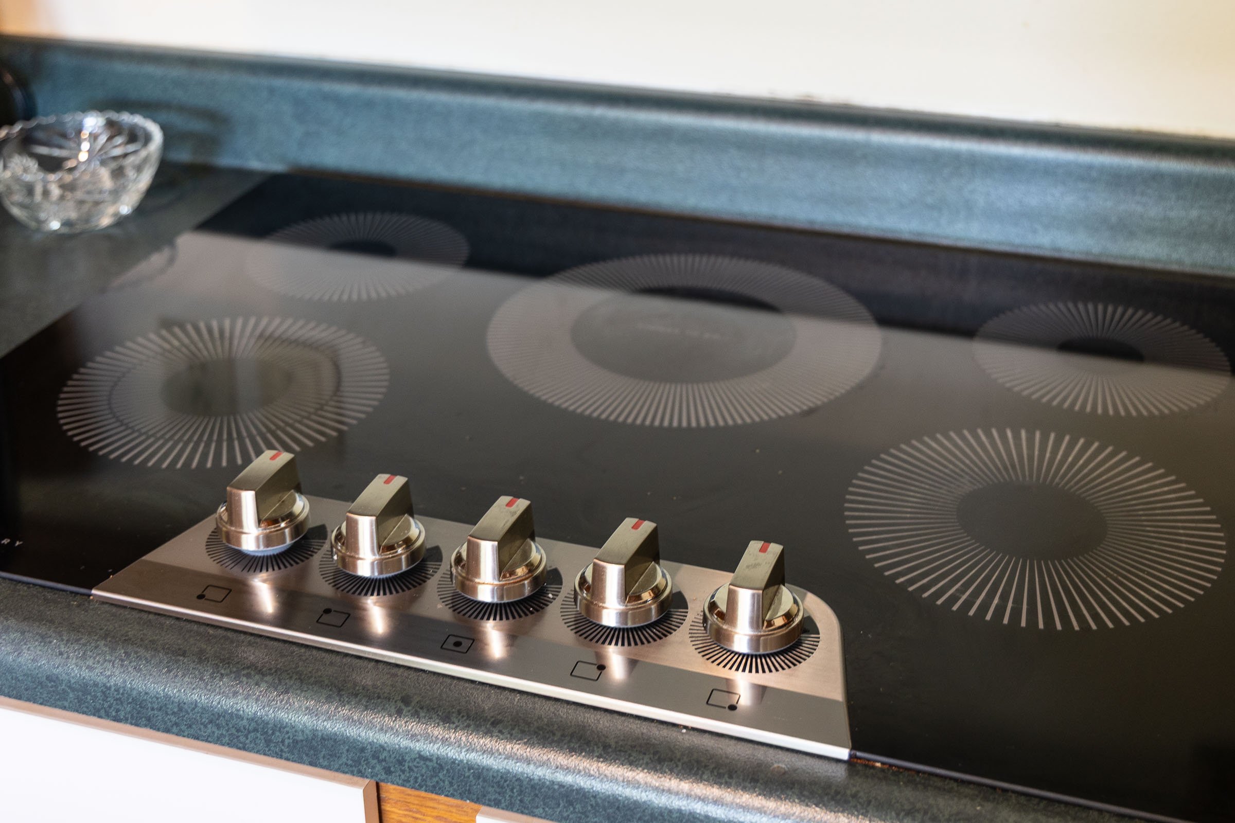 A black electric stove with four burners and silver control knobs in a kitchen.