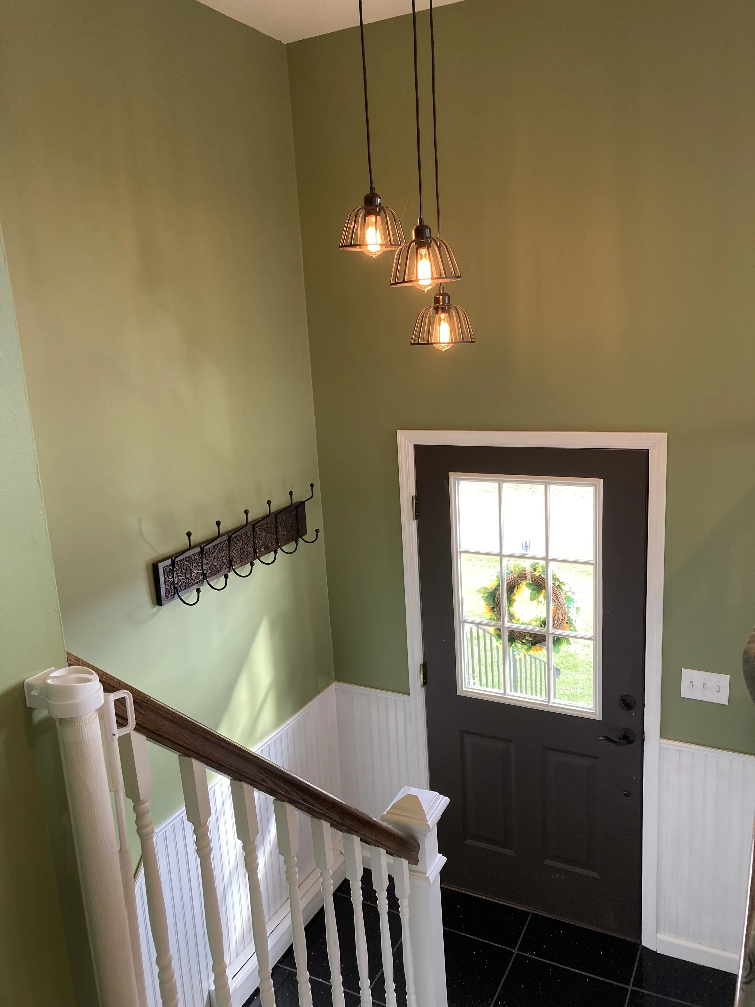 Whitney's Old House Before: Entryway Before the Transformation. The Wall on the Left Was the Wall of a Closet. Once Painted a Forest Green with Industrial Chic Lighting, Door Painted Chalky Brown, & White Wood Paneling Trim. The Stairs Had Wood Spind
