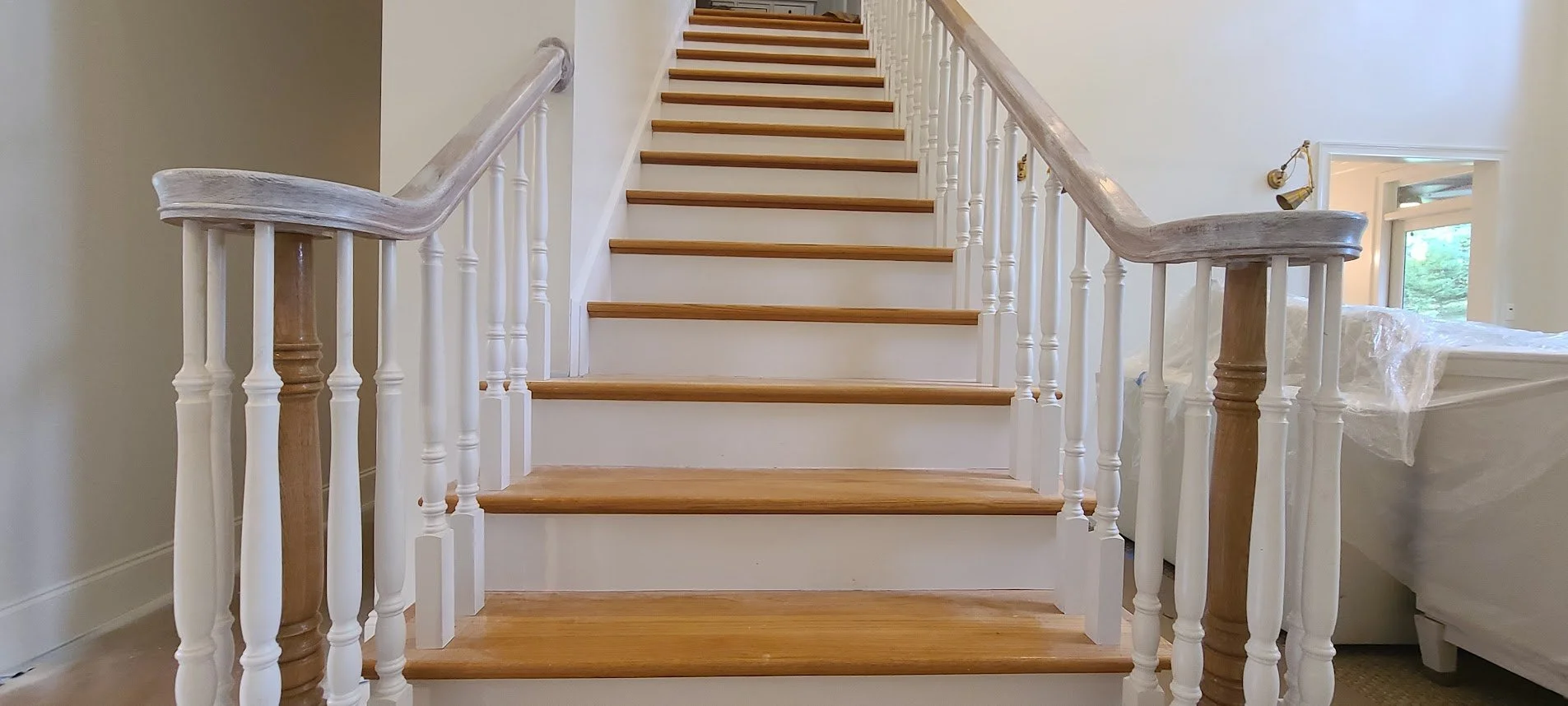 Interior view of a wooden staircase with white spindles and brown handrails, leading upwards in a residential home.