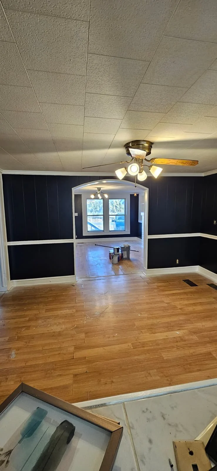 After: An interior painting project in Sardis City, Alabama that entailed painting white wood paneling a high gloss black, with high gloss white trim to contrast the look. This was the dining room area. 