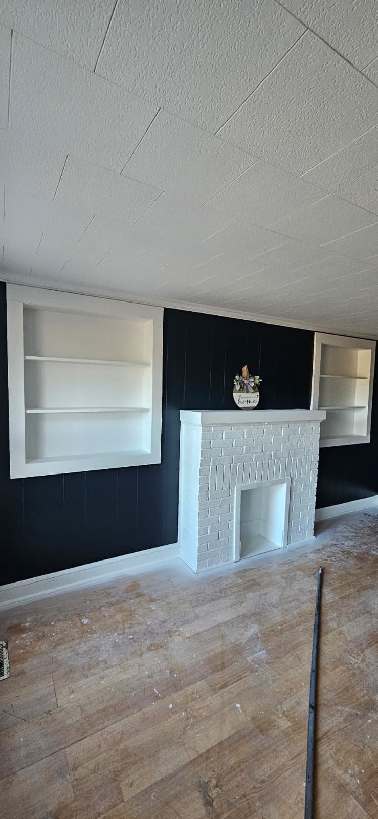This brick fireplace was painted as part of an interior painting project in Sardis City, Alabama. The wood plank walls were painted a high gloss black, and the shelves and trim were painted white to match the fireplace and contrast the black walls.